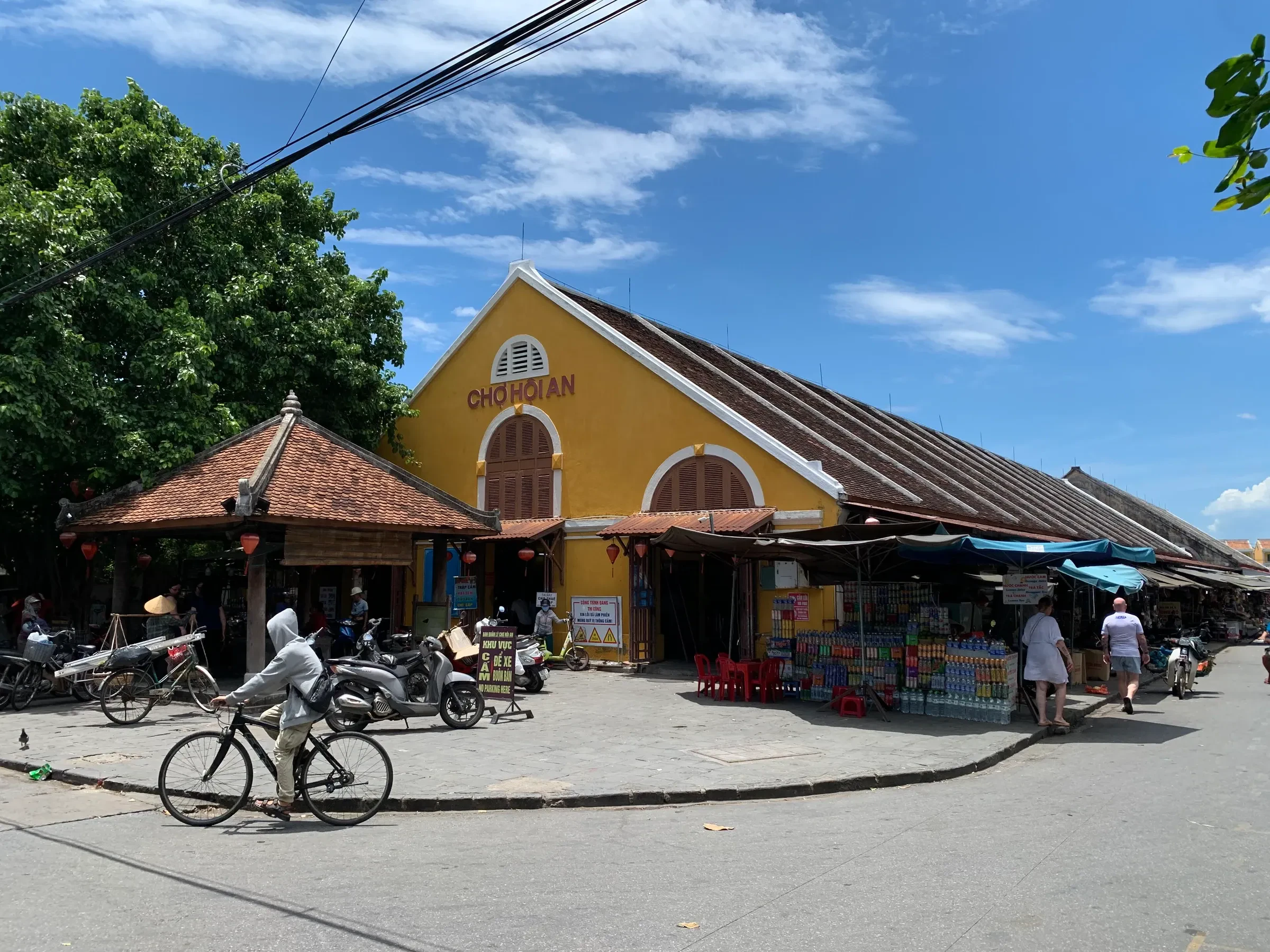 The yellow market hall at Hoi An Market, with a cyclist crossing the square