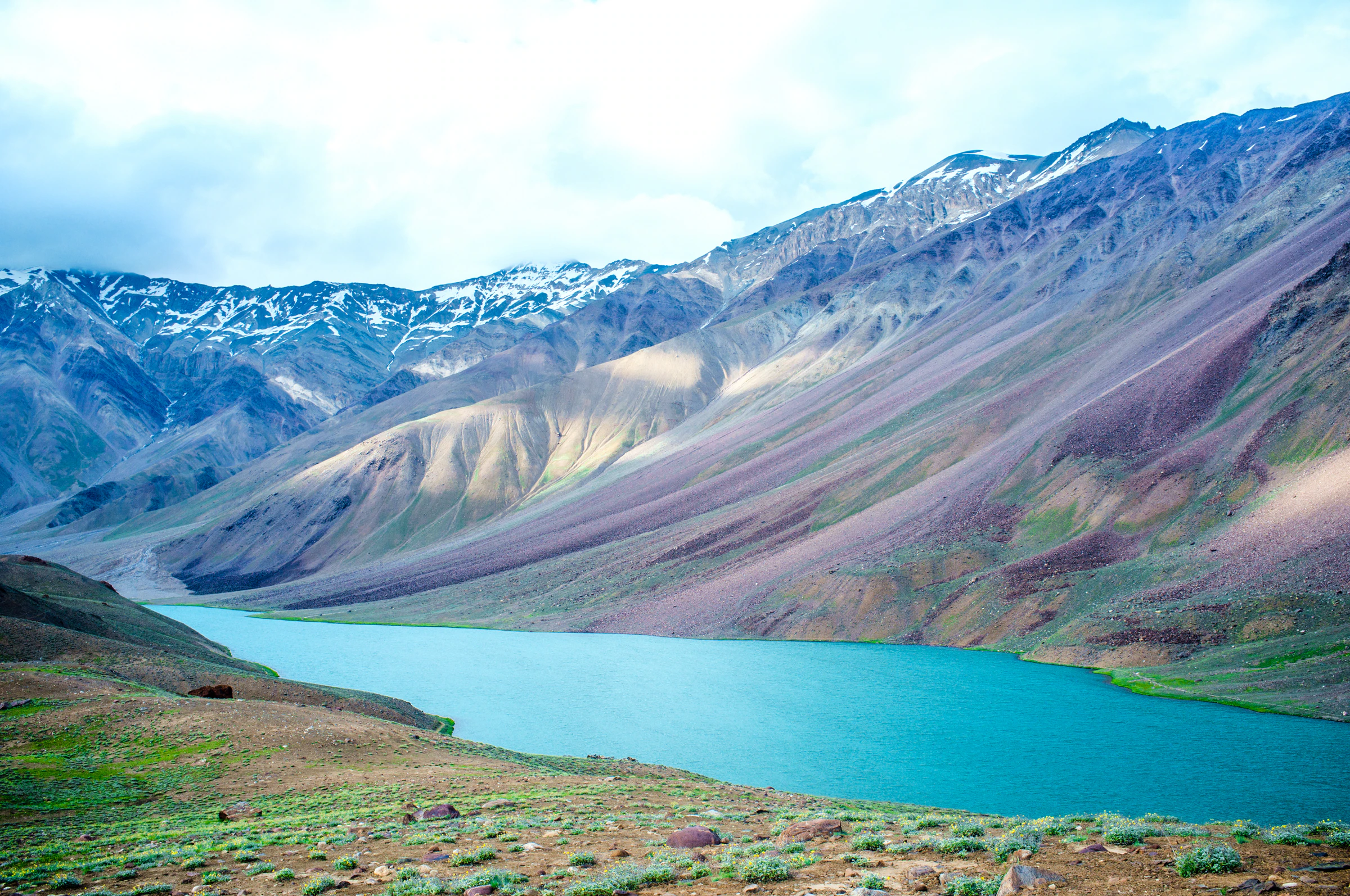 Chandratal lake, with purple and brown mountain slopes rising behind it