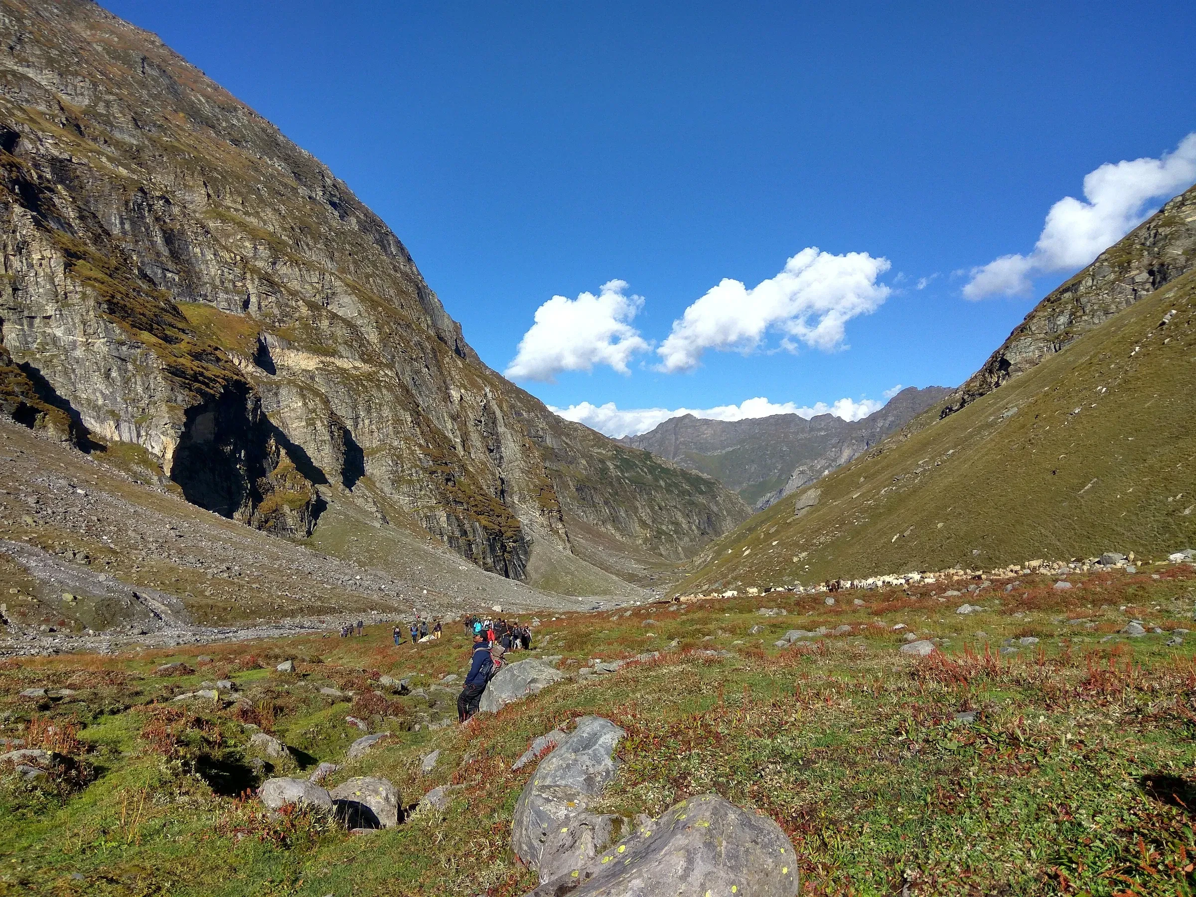 A trekker walking through a green valley on the way up to Hampta Pass