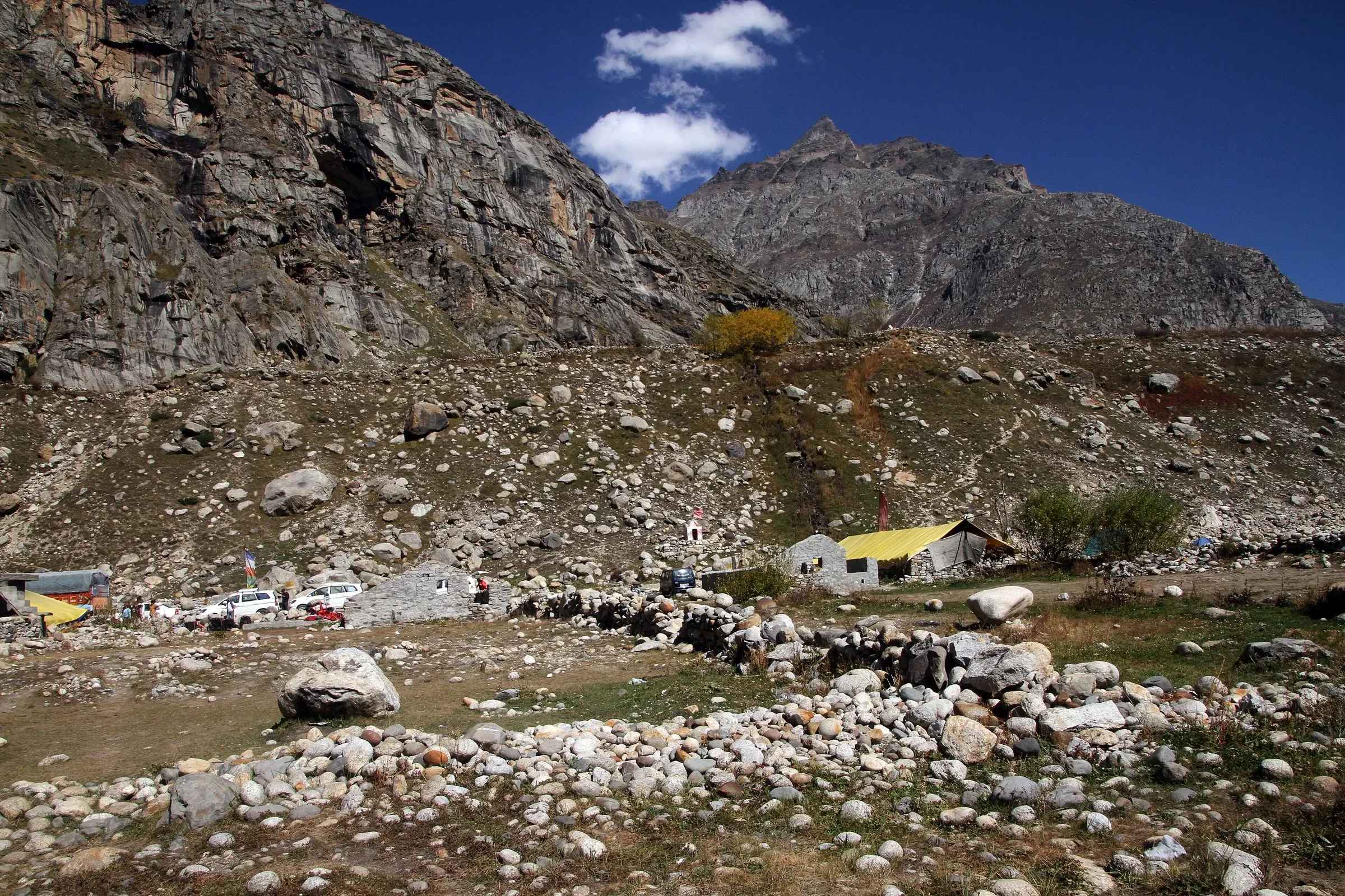 The roadside settlement of Chhatru, with huts and cars below rocky slopes