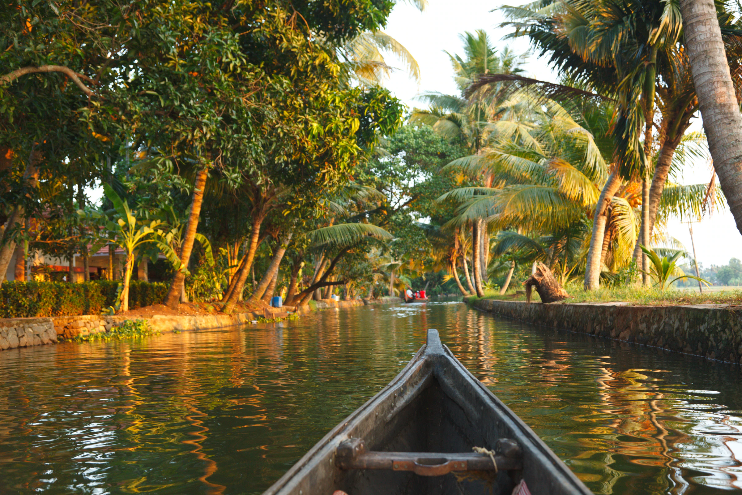A wooden canoe heading down a narrow backwater canal