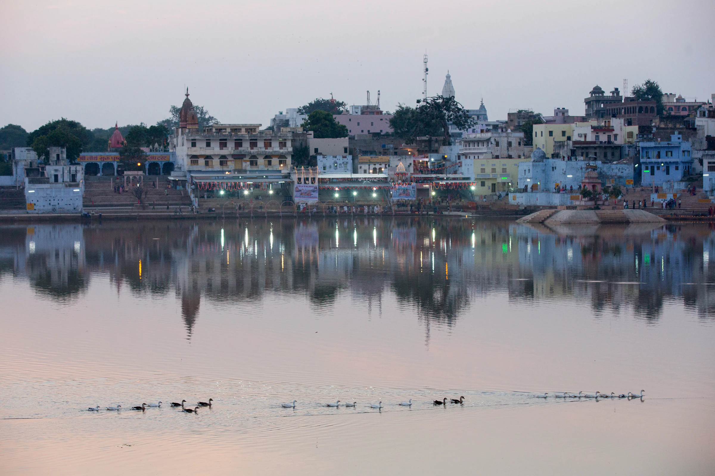 Pushkar's lakeside buildings reflected in the water at dusk