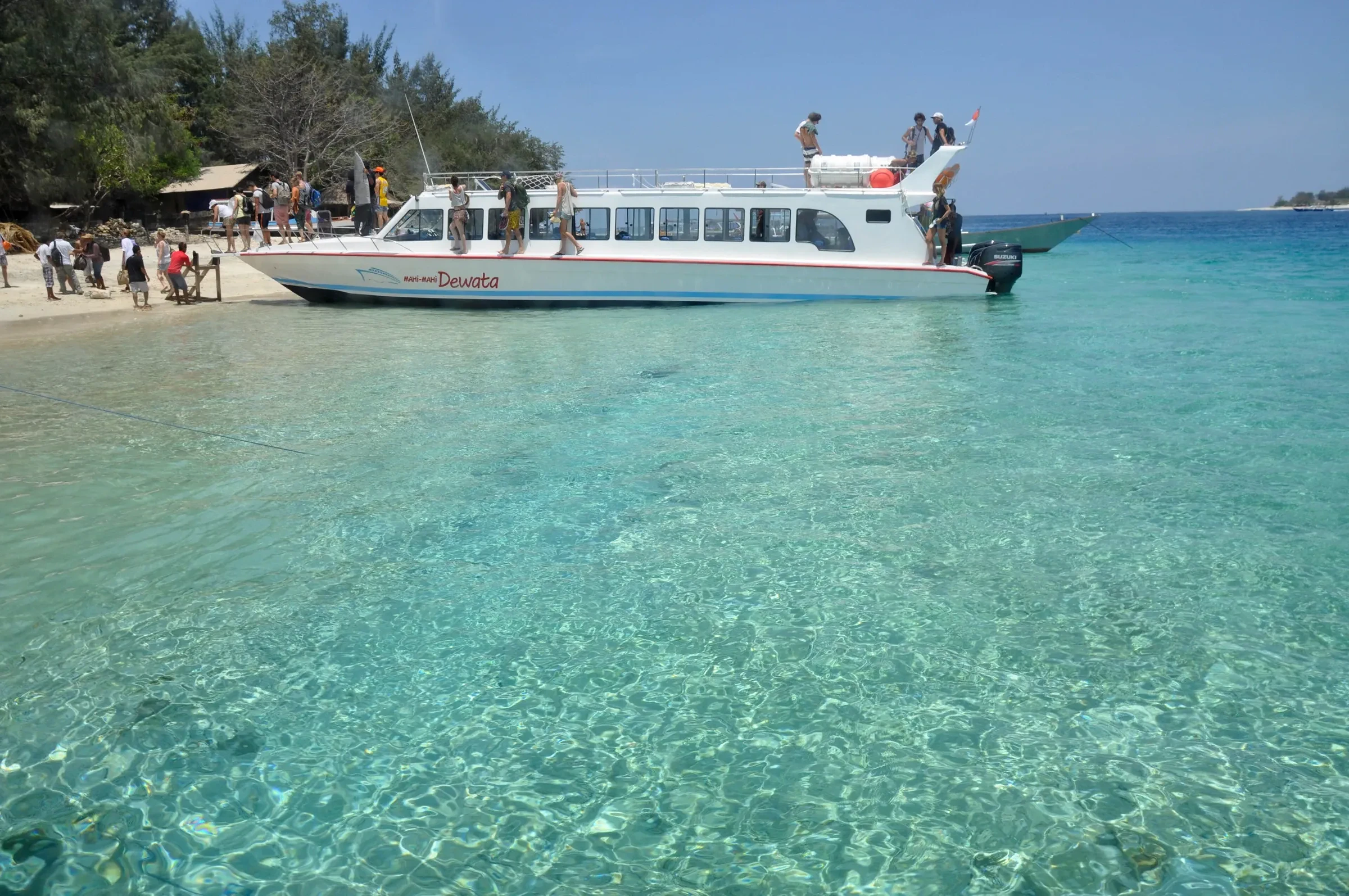 A fast boat waiting in turquoise shallows off a Gili beach