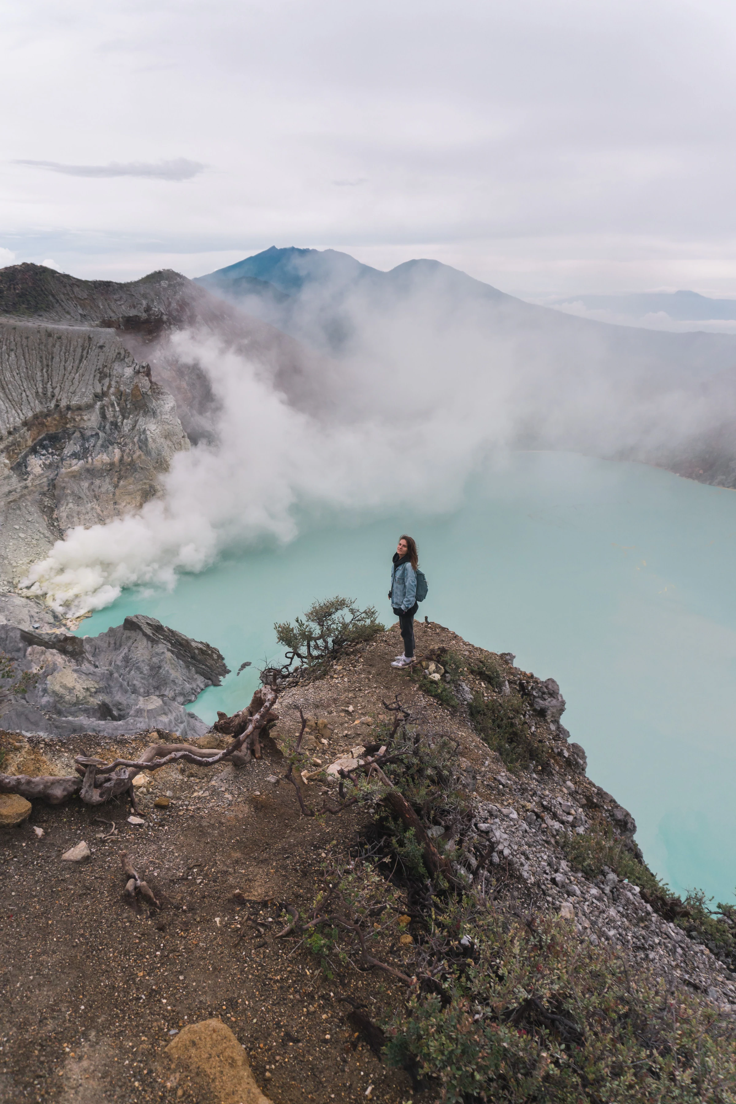 A hiker above the turquoise sulphur lake at Ijen