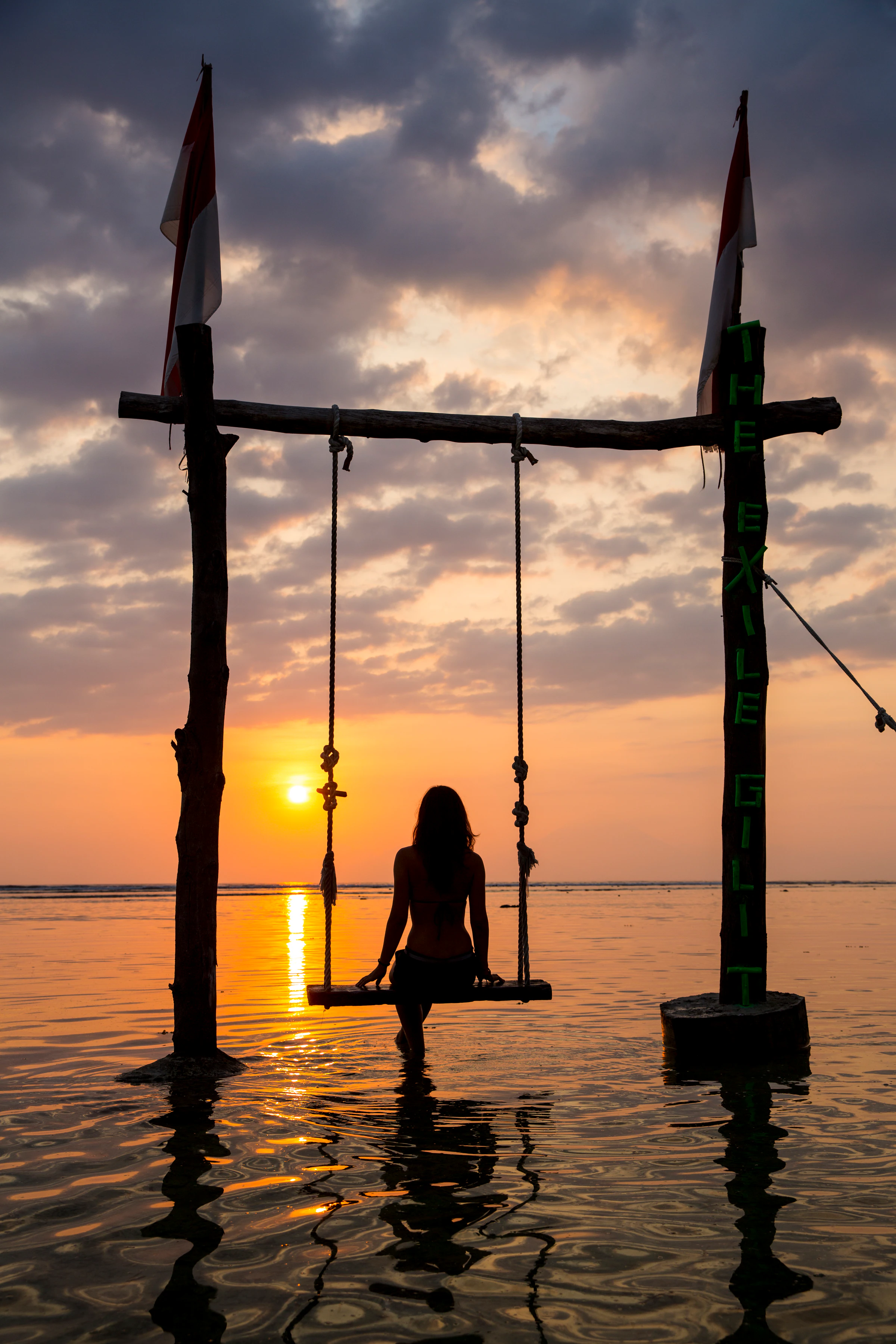 A traveller on a beach swing at sunset on Gili Trawangan