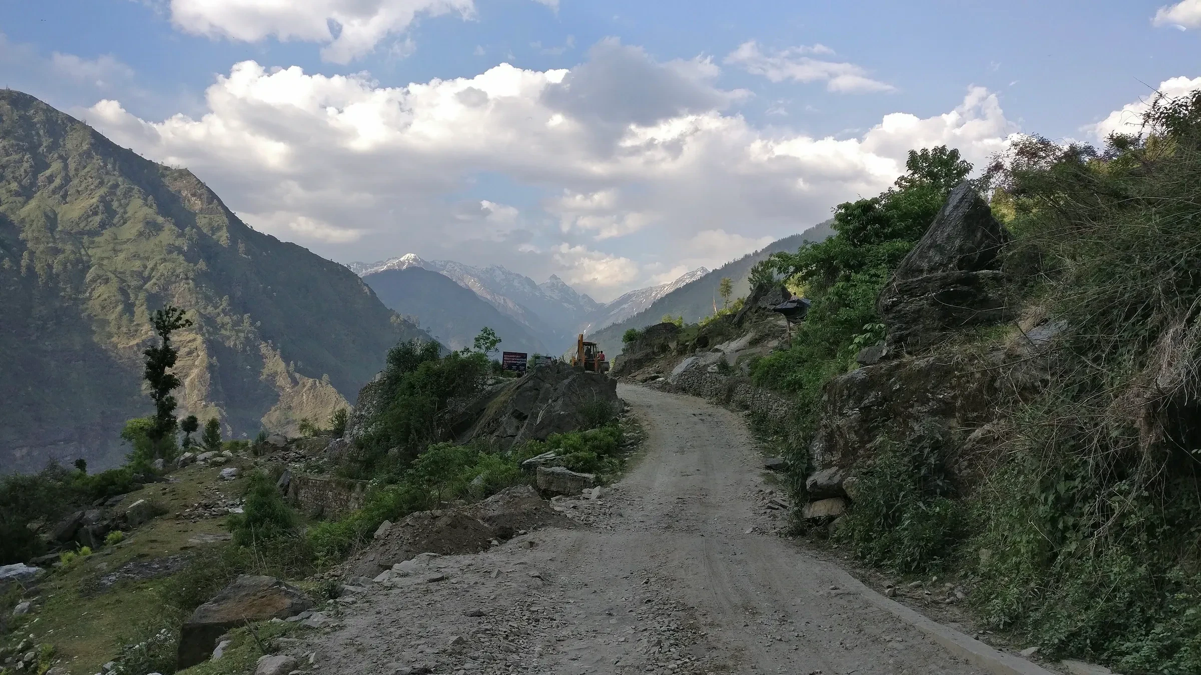A gravel mountain road winding along a forested slope on the way to Sankri