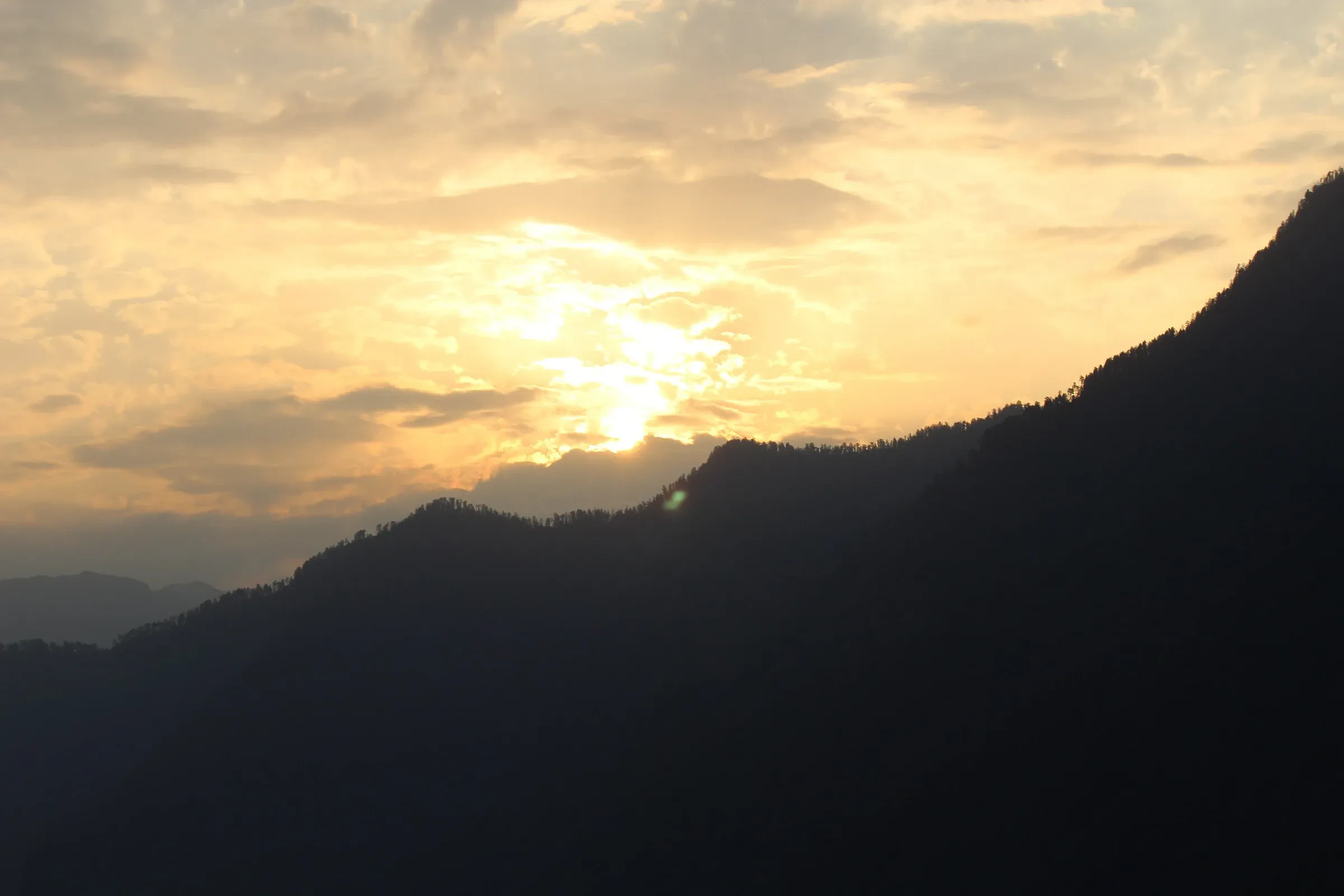 The sun setting behind a mountain ridge at Sankri