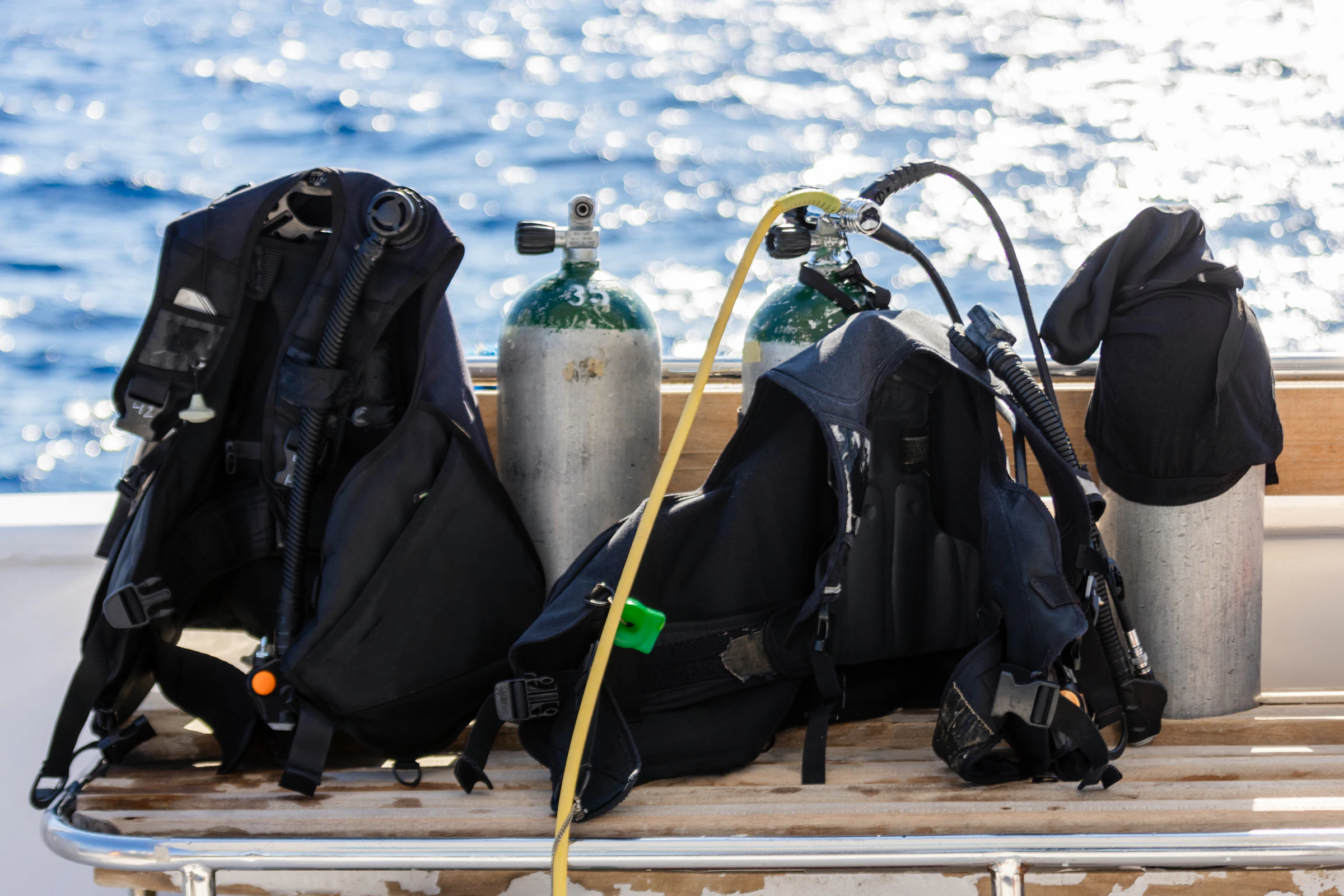 Scuba tanks and buoyancy jackets laid out on a dive boat deck