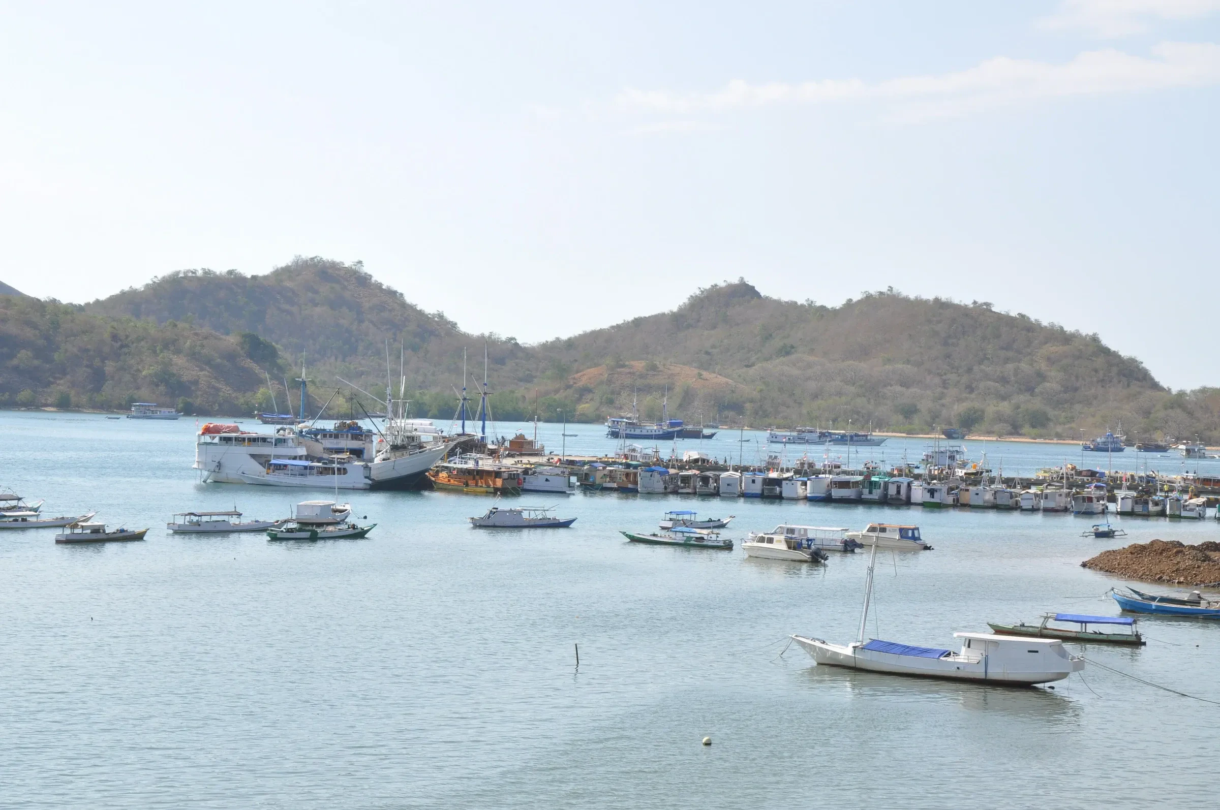 Small boats moored in Labuan Bajo harbour with dry hills behind