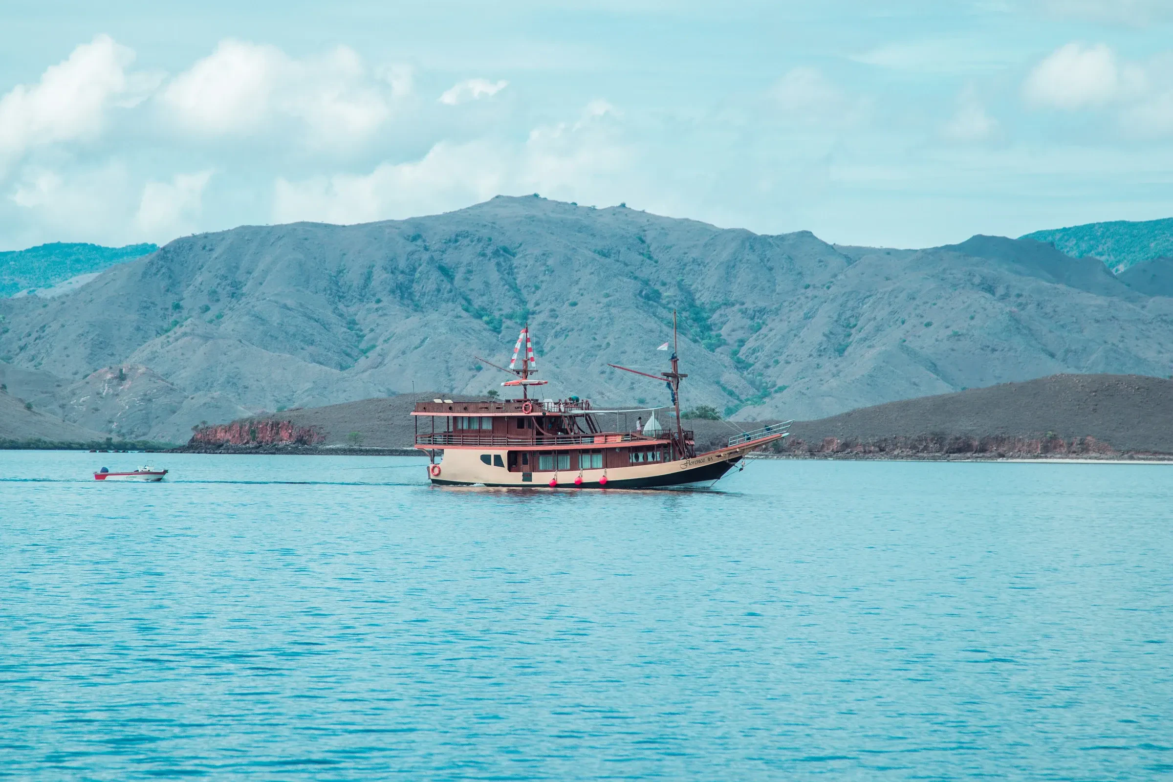 A wooden phinisi boat anchored in turquoise water off the Flores coast near Labuan Bajo