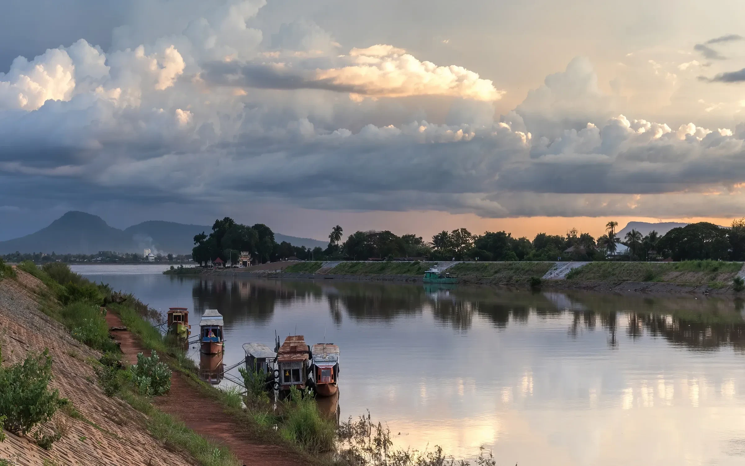 Boats moored on the Xe Don River at sunset in Pakse under a cloudy sky