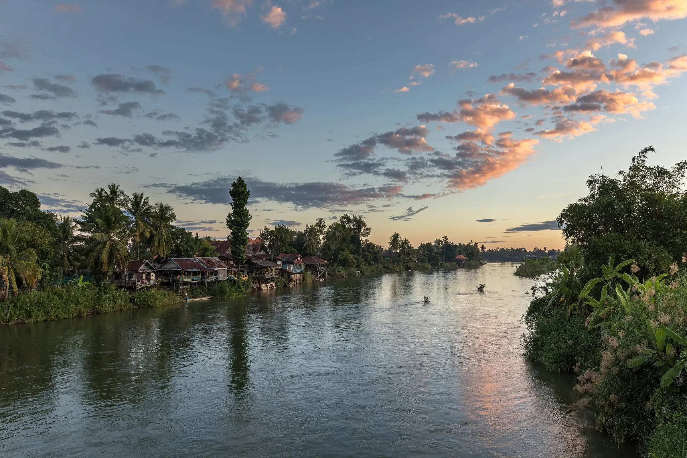 Stilt houses and wooden boats on the Mekong bank of Don Det at sunrise