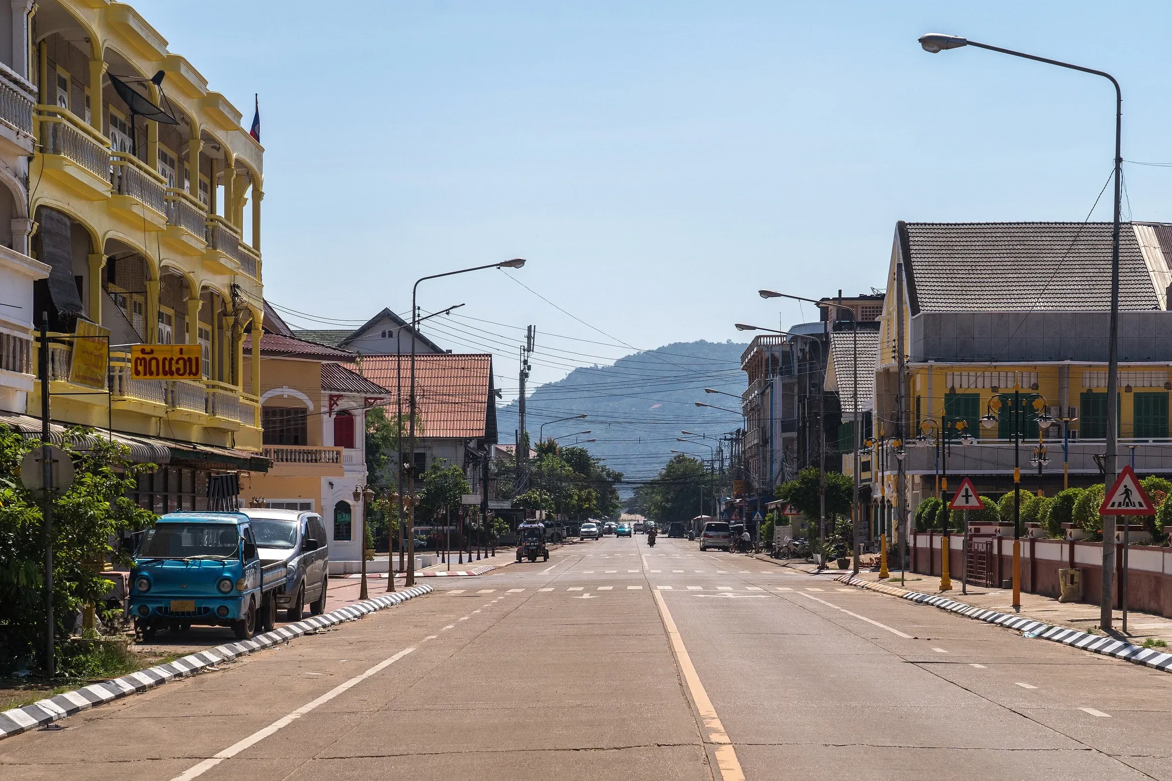 Yellow French colonial shophouses on a wide street in Pakse