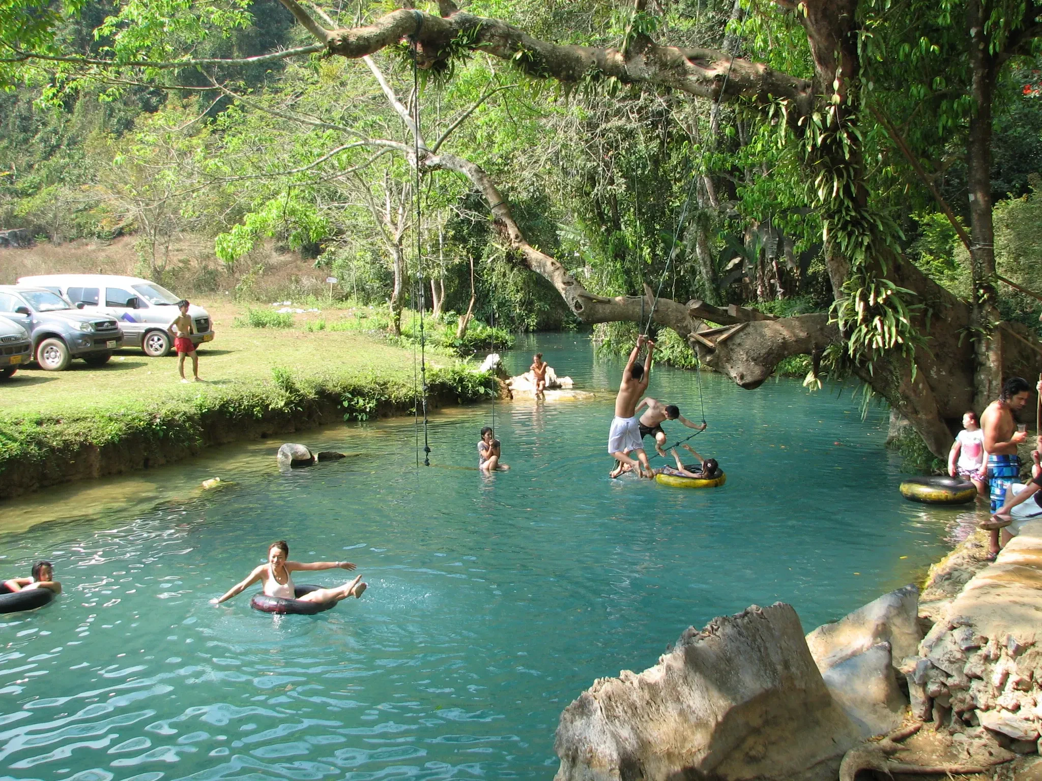 Swimmers floating on tubes in the turquoise water of the Blue Lagoon near Vang Vieng