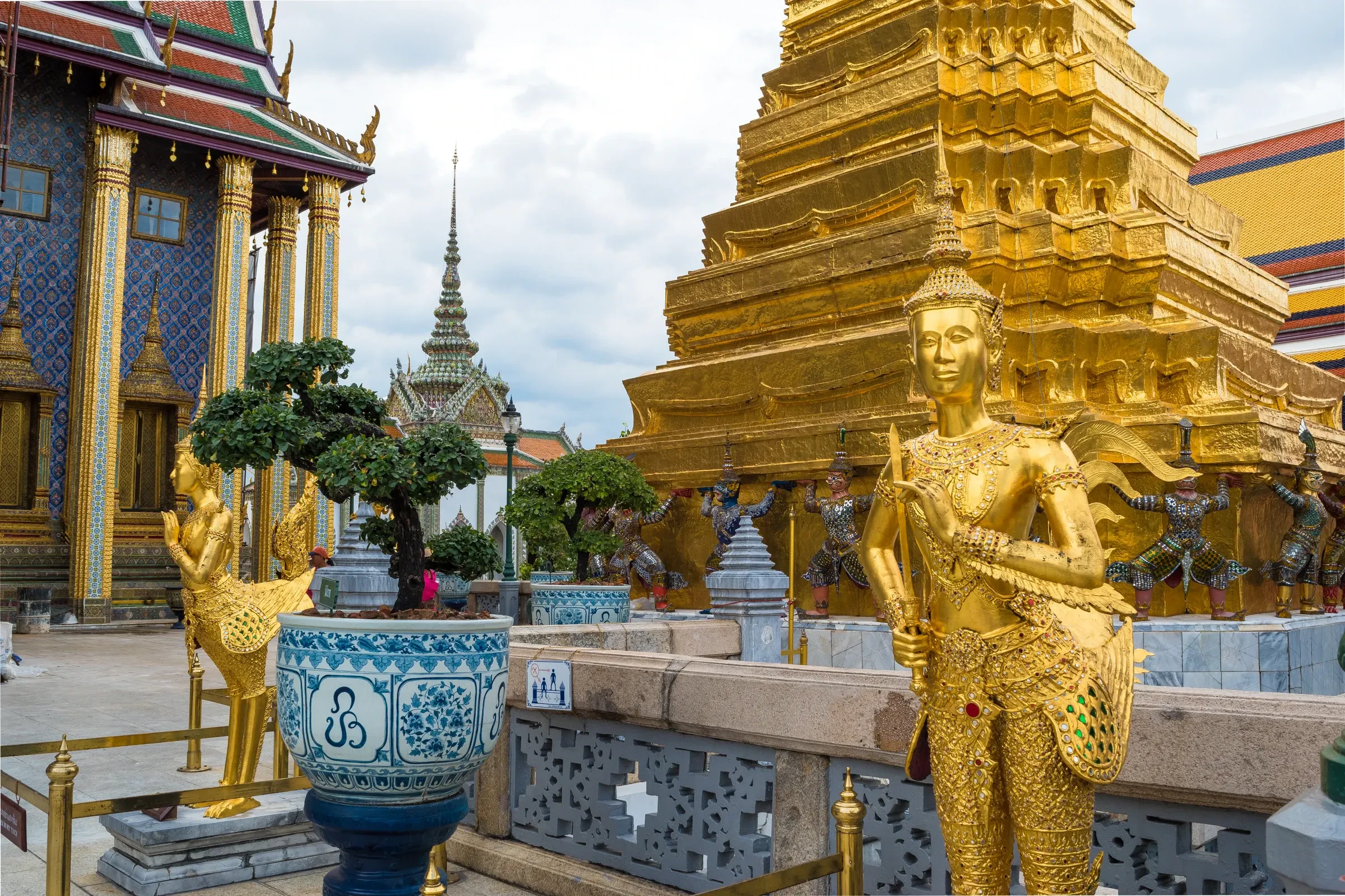 Golden guardian statues and a gilded chedi at the Grand Palace in Bangkok
