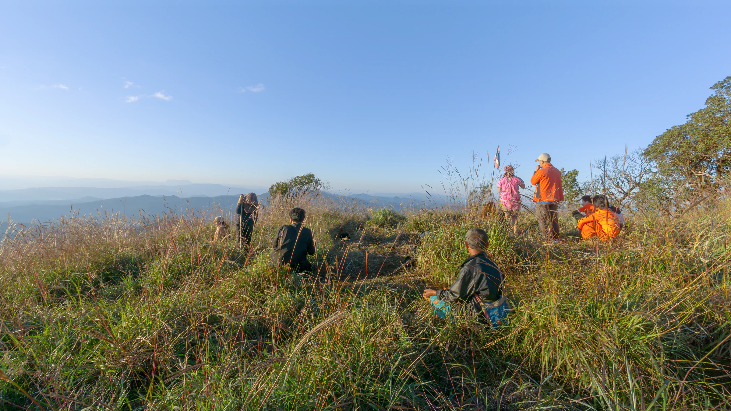 Hikers resting on a grassy hilltop with a mountain view