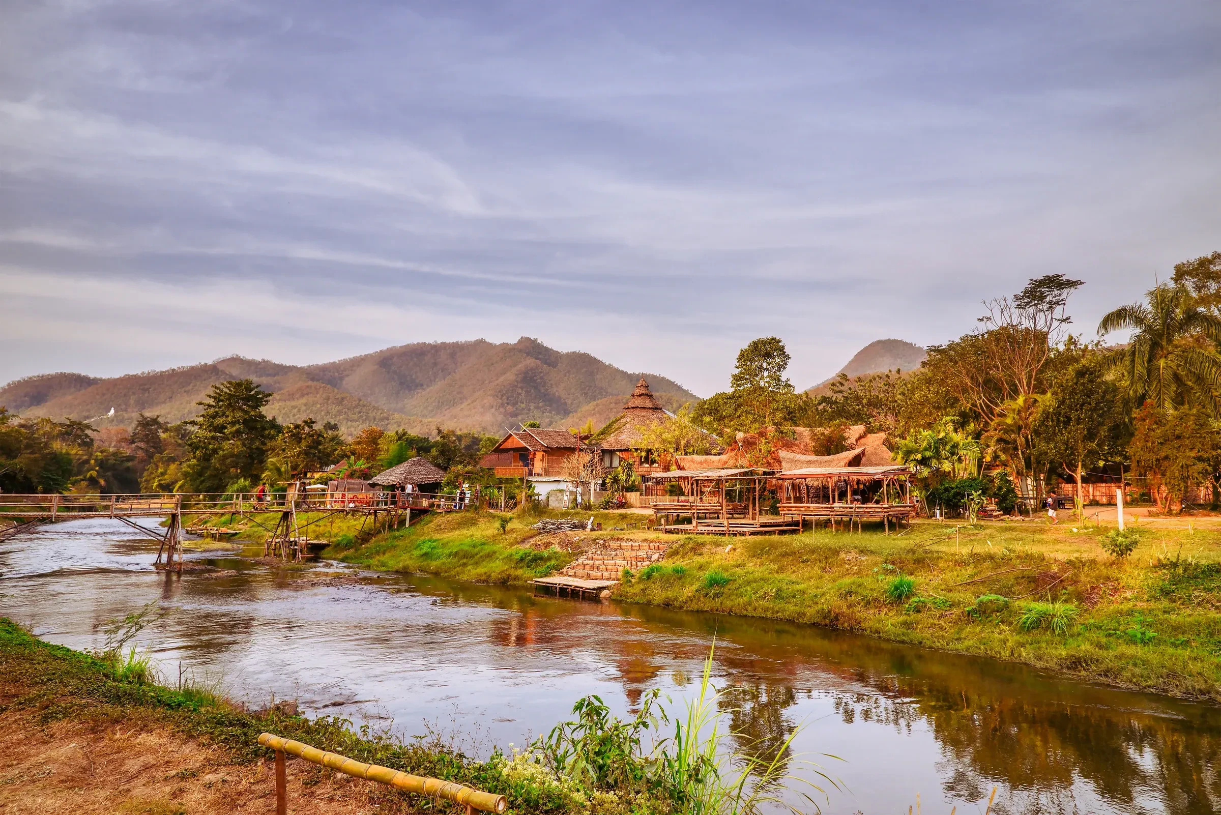 The Pai River with guesthouses on its bank and mountains behind