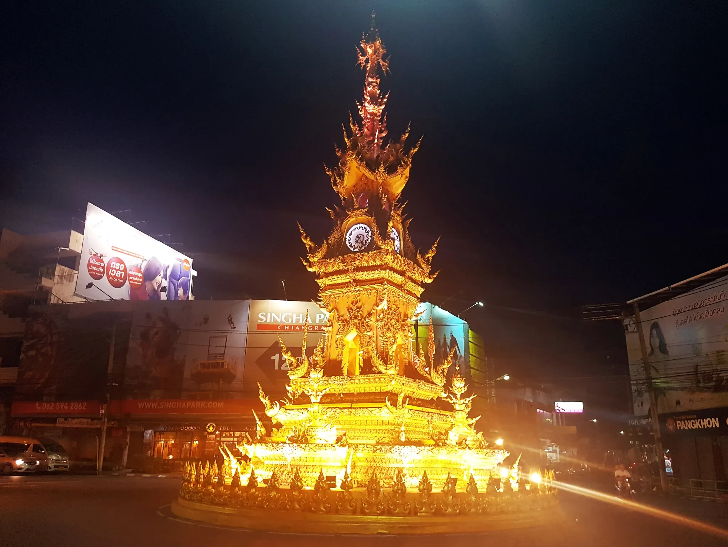 The golden clock tower in the centre of Chiang Rai lit up at night