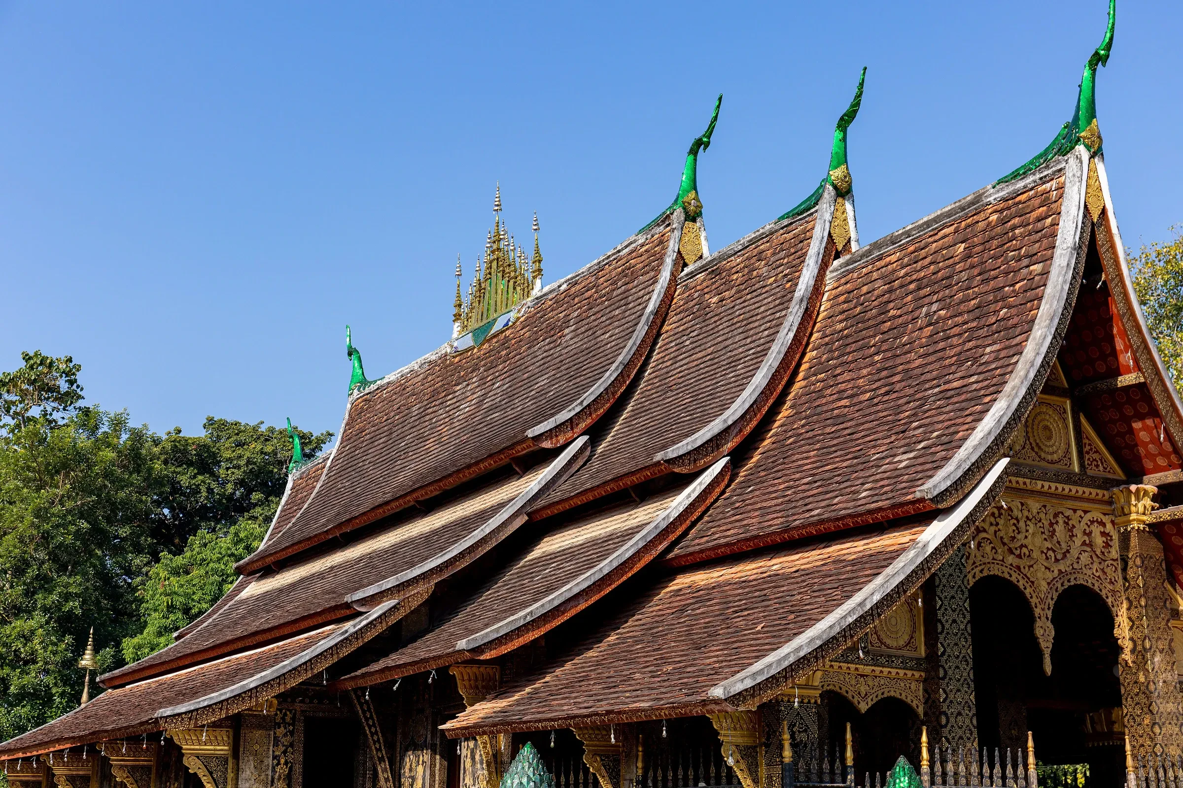 The tiered roofs of Wat Xieng Thong in Luang Prabang under a blue sky