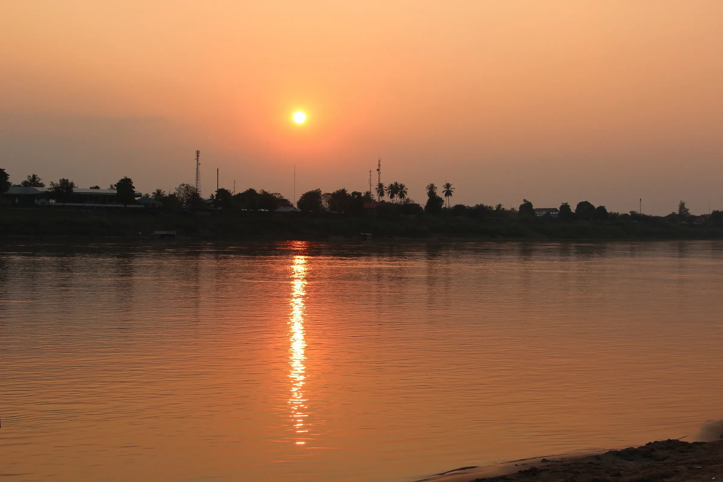 The sun setting over the Mekong at Vientiane with the river calm below