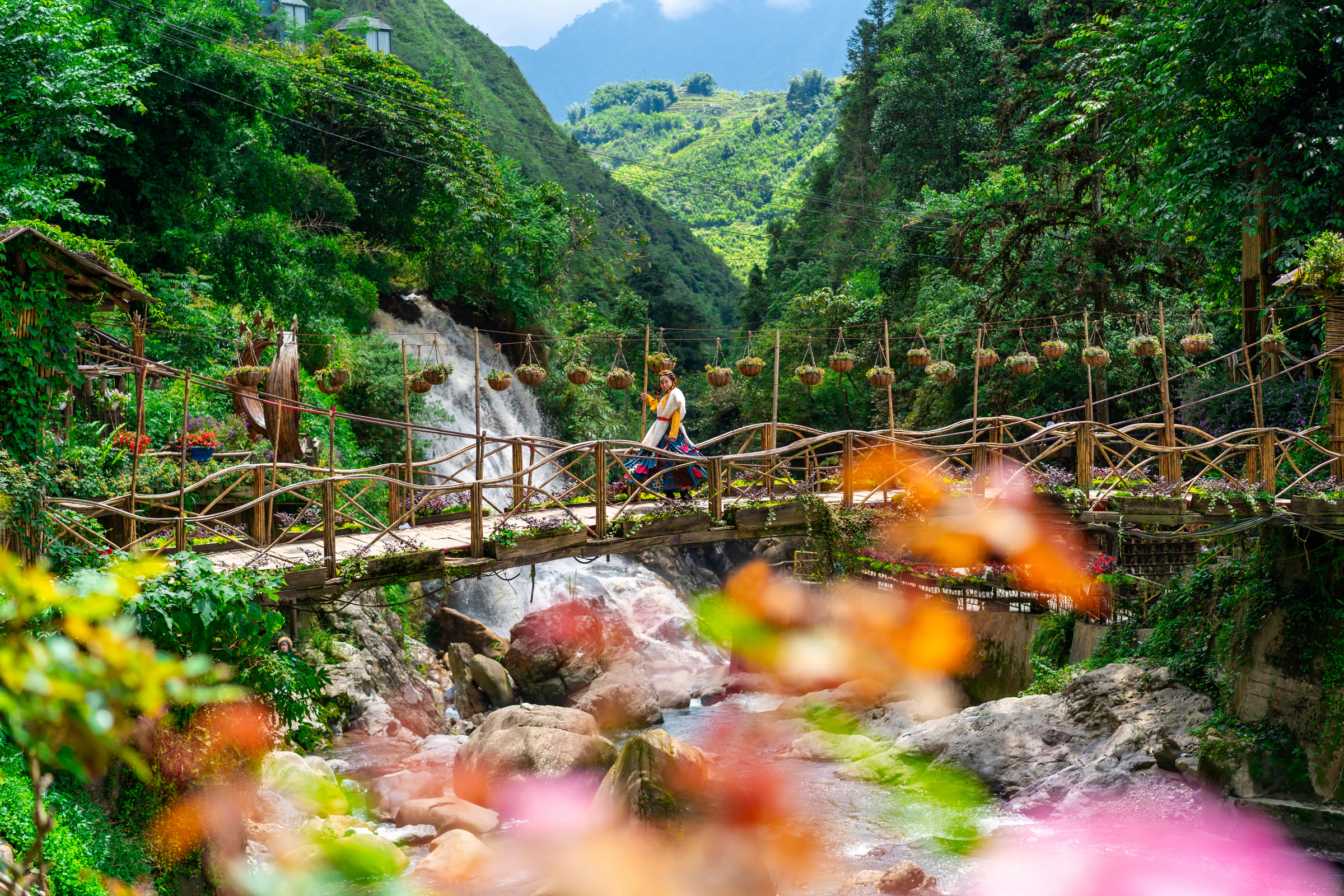A wooden bridge over a stream near a waterfall in the mountains