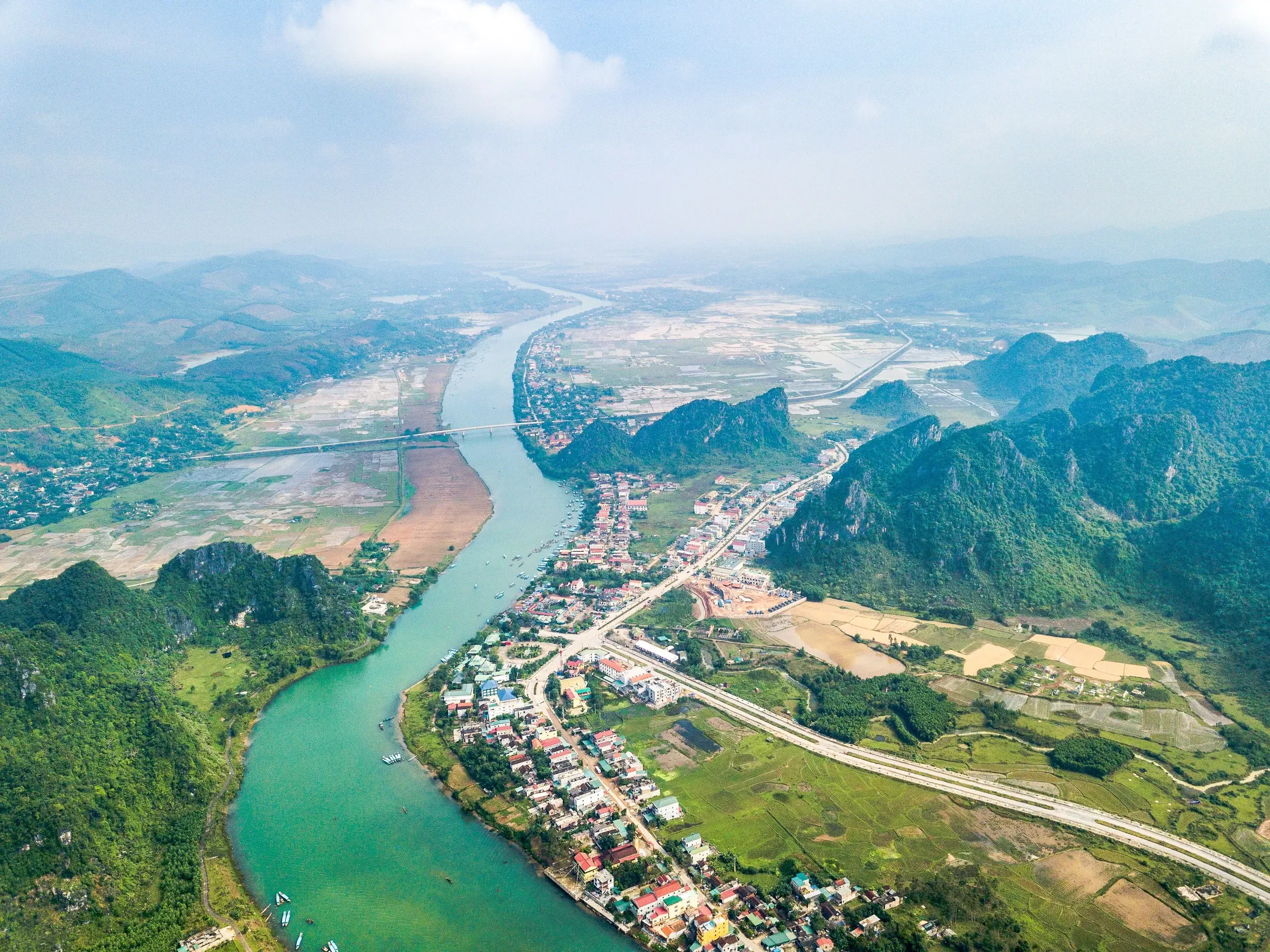 The green Son River running past a town and karst hills near Phong Nha