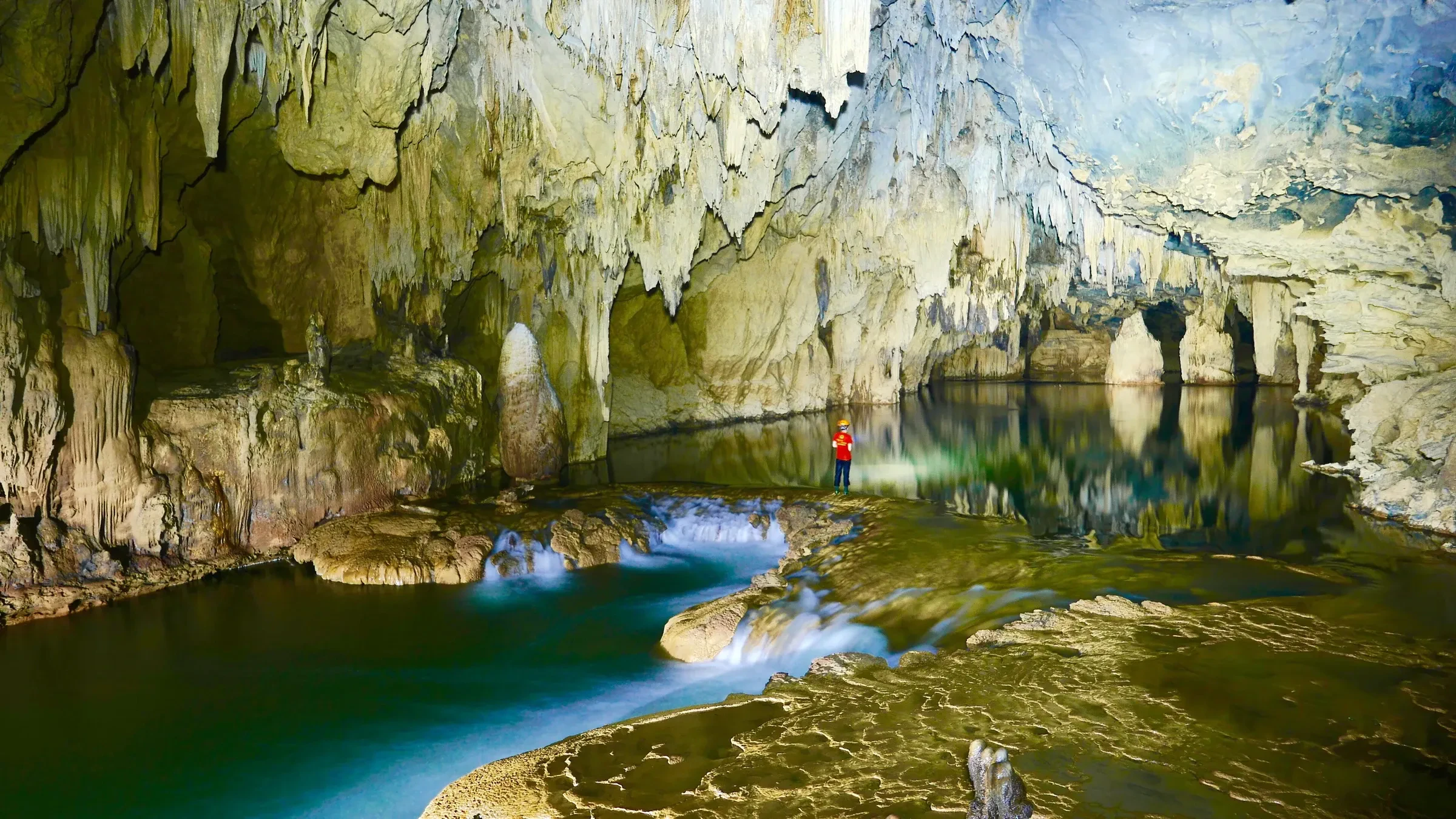 A turquoise pool and cave formations in Hang Kim, part of the Tu Lan caves