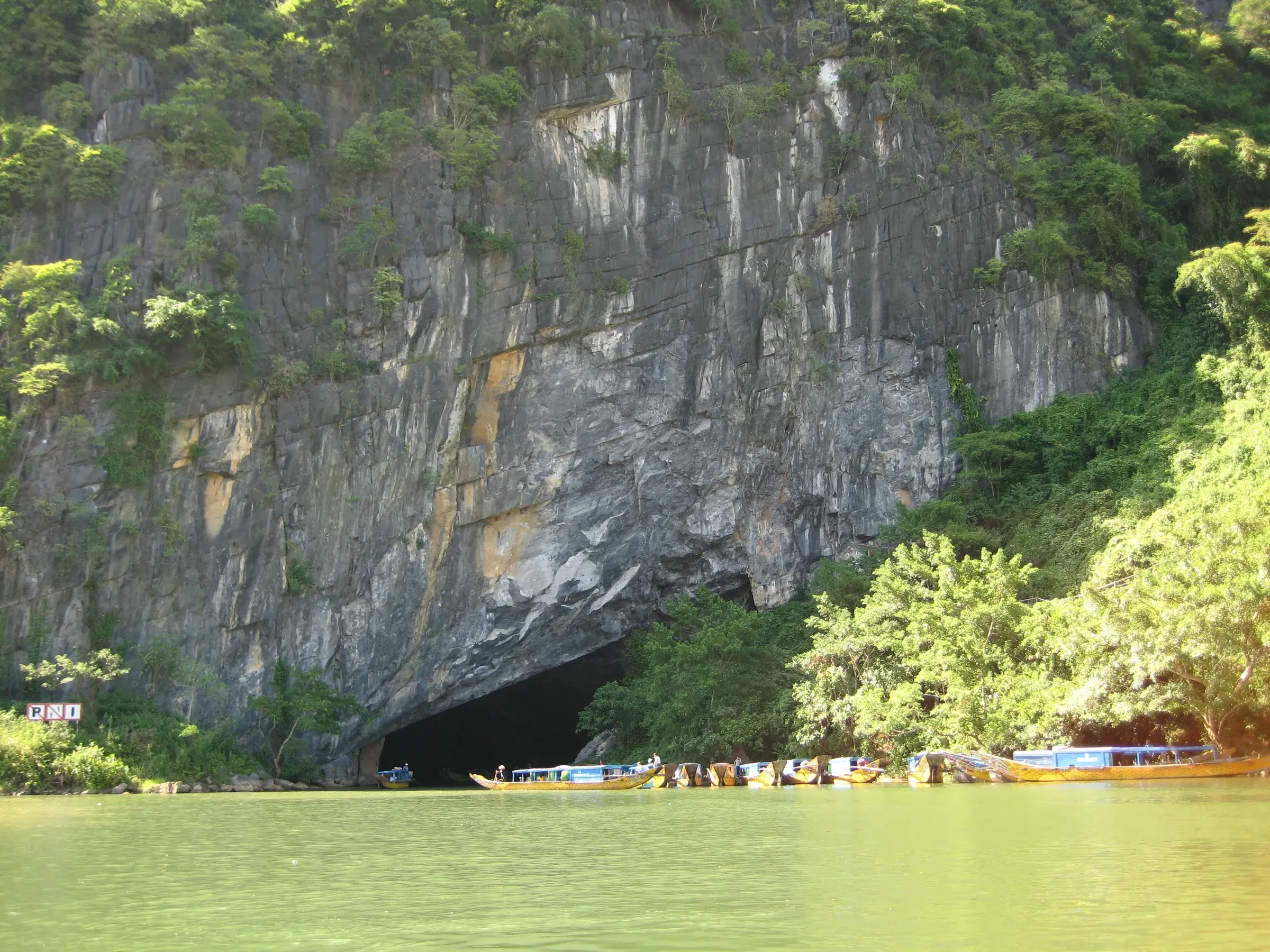 A limestone cliff and cave mouth above the green Son River in Phong Nha