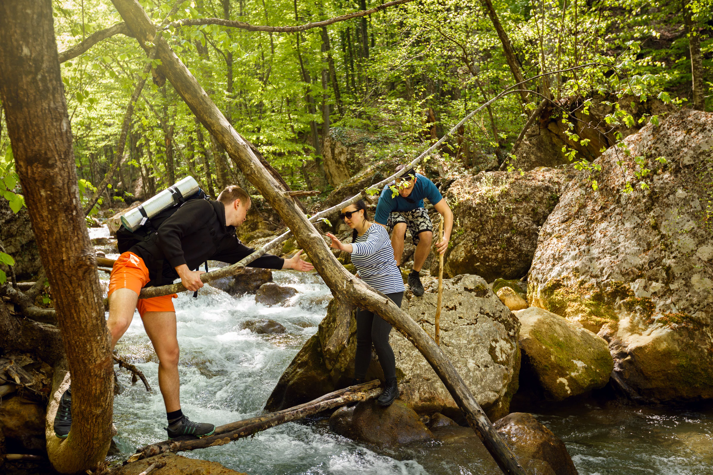 Group trekking and crossing a rocky river stream in the jungle