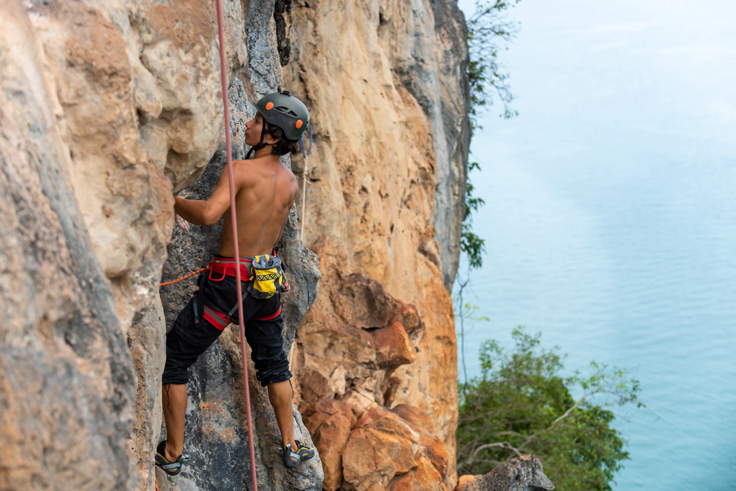 A climber on a limestone sport route above the sea at Railay