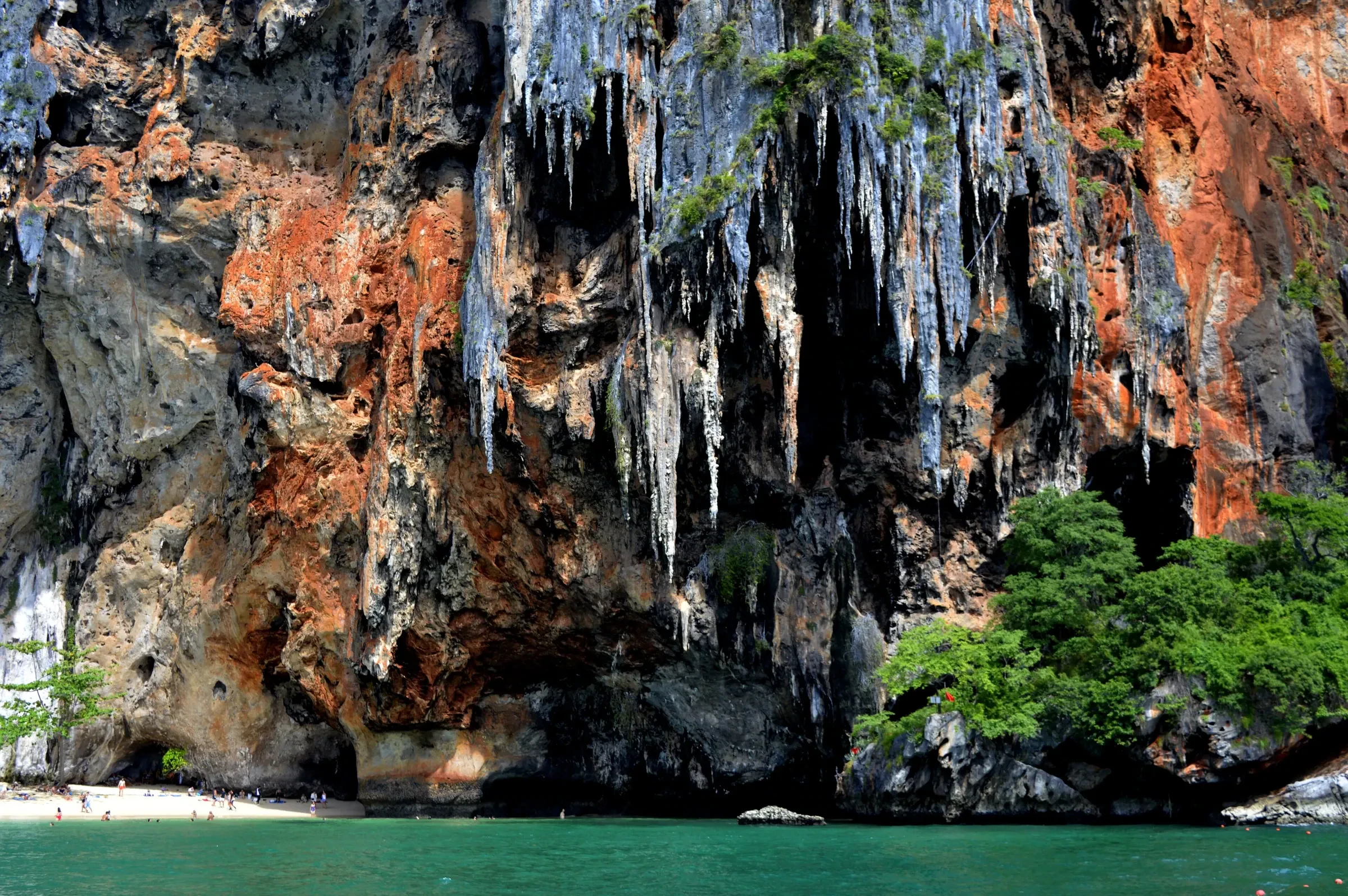 Orange and grey limestone cliffs with stalactites rising from the sea at Railay