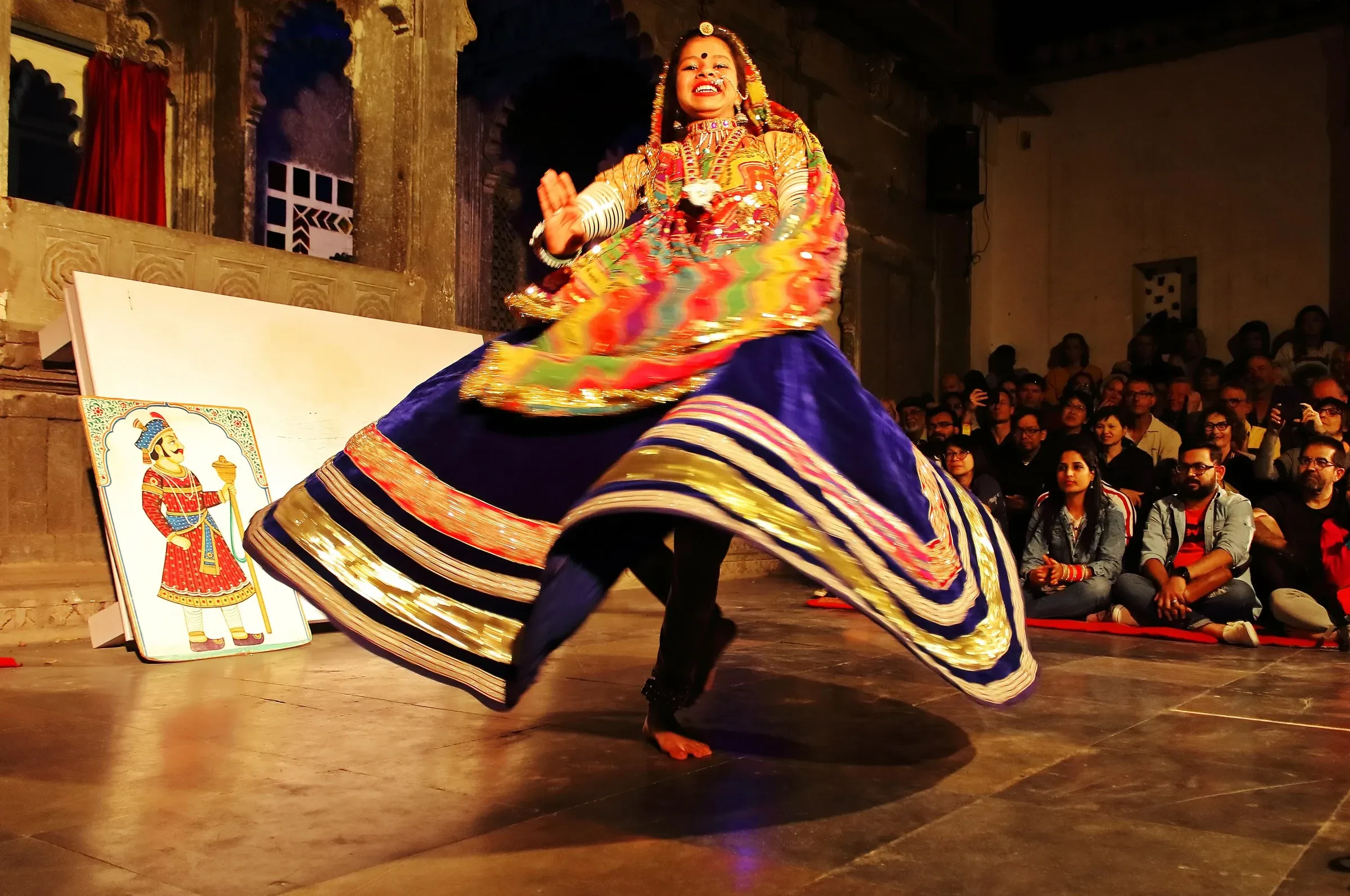 A folk dancer in a swirling skirt on stage in the courtyard of Bagore ki Haveli in Udaipur