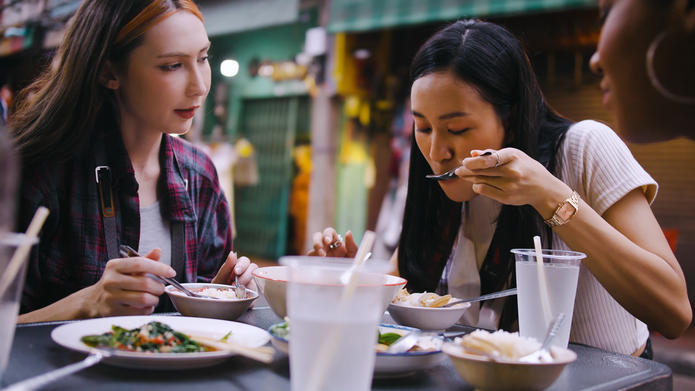 Friends sharing plates at a street-food table in Bangkok
