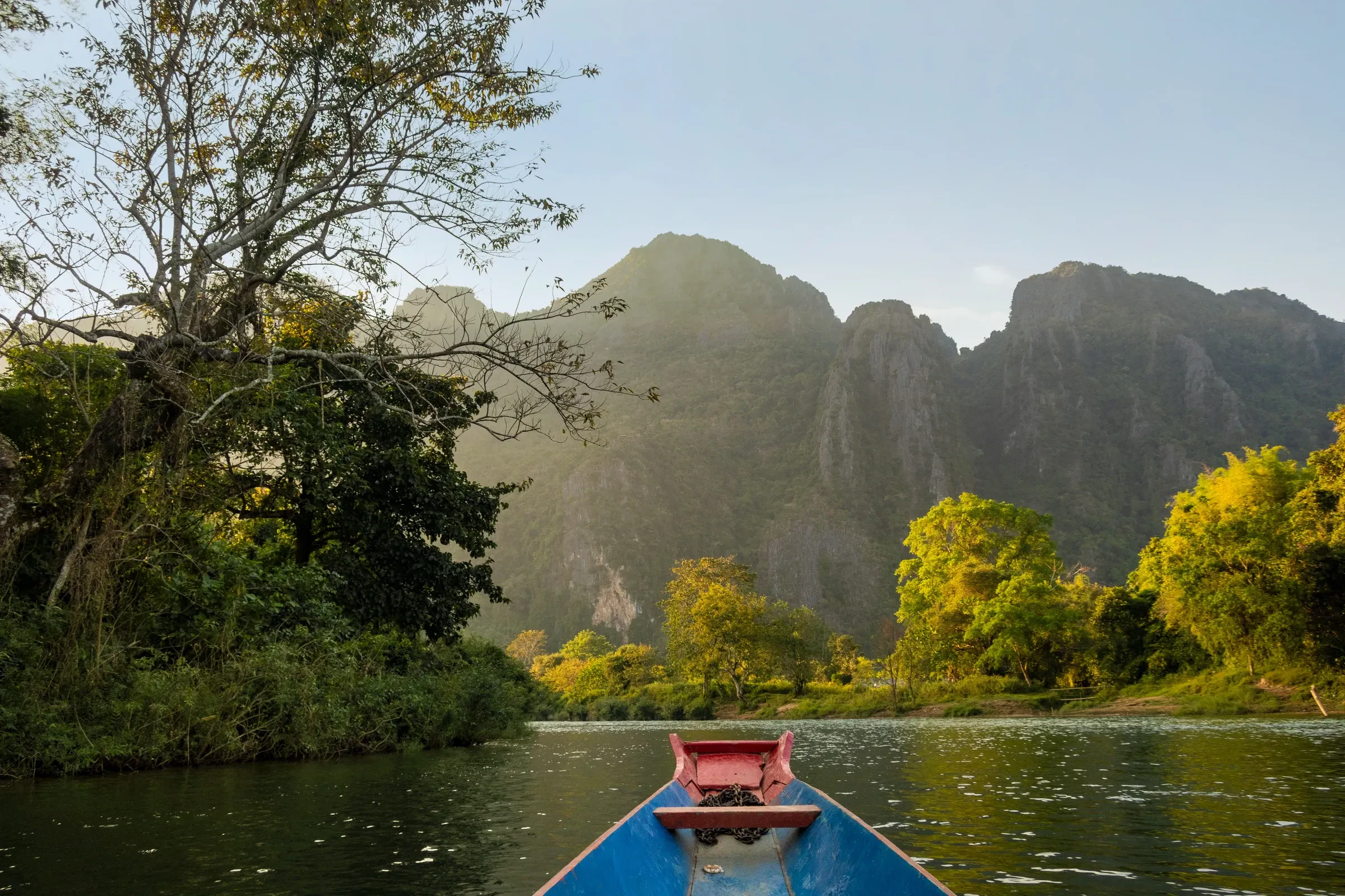 The bow of a long boat on the Nam Song below limestone peaks in Vang Vieng