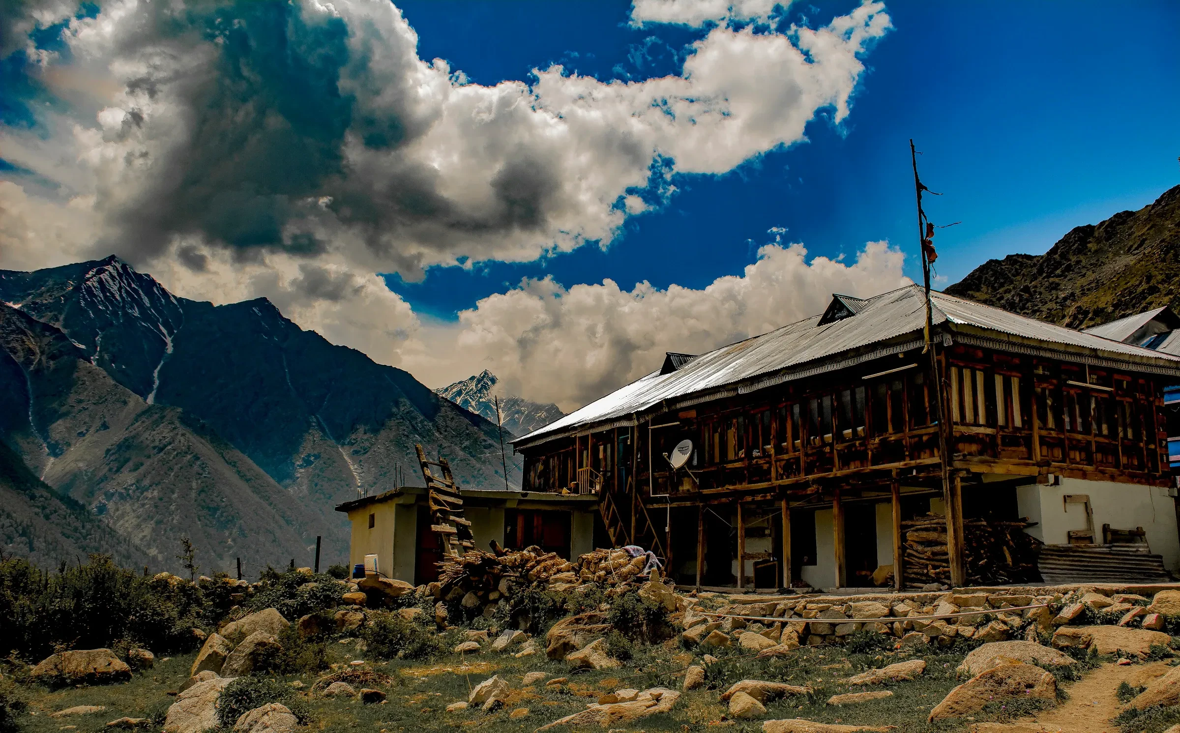 A traditional wooden house in Chitkul with snow mountains behind it