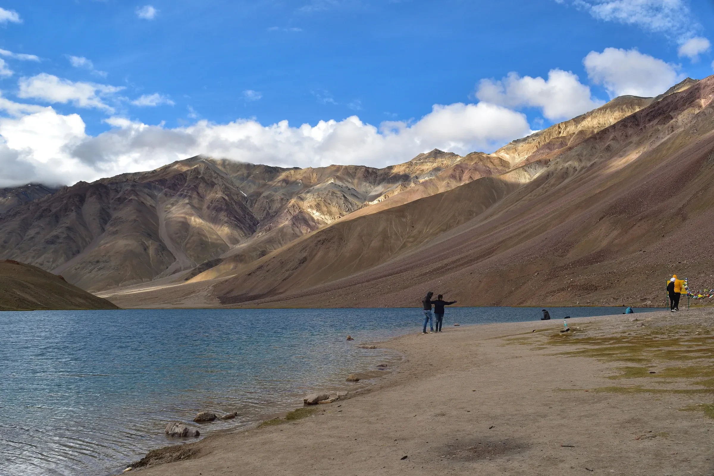 Chandra Taal lake with brown mountains rising behind its shore, Himachal Pradesh