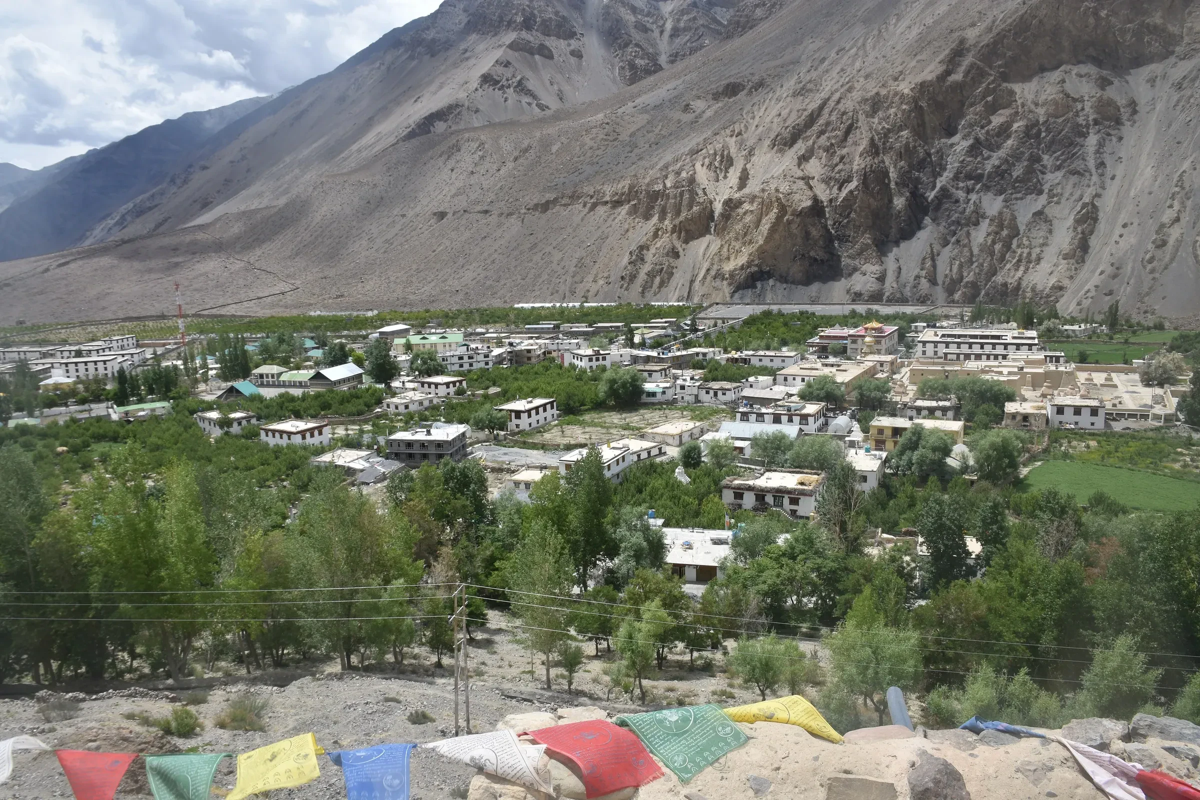 Tabo village in the Spiti Valley below dry mountains, seen past prayer flags