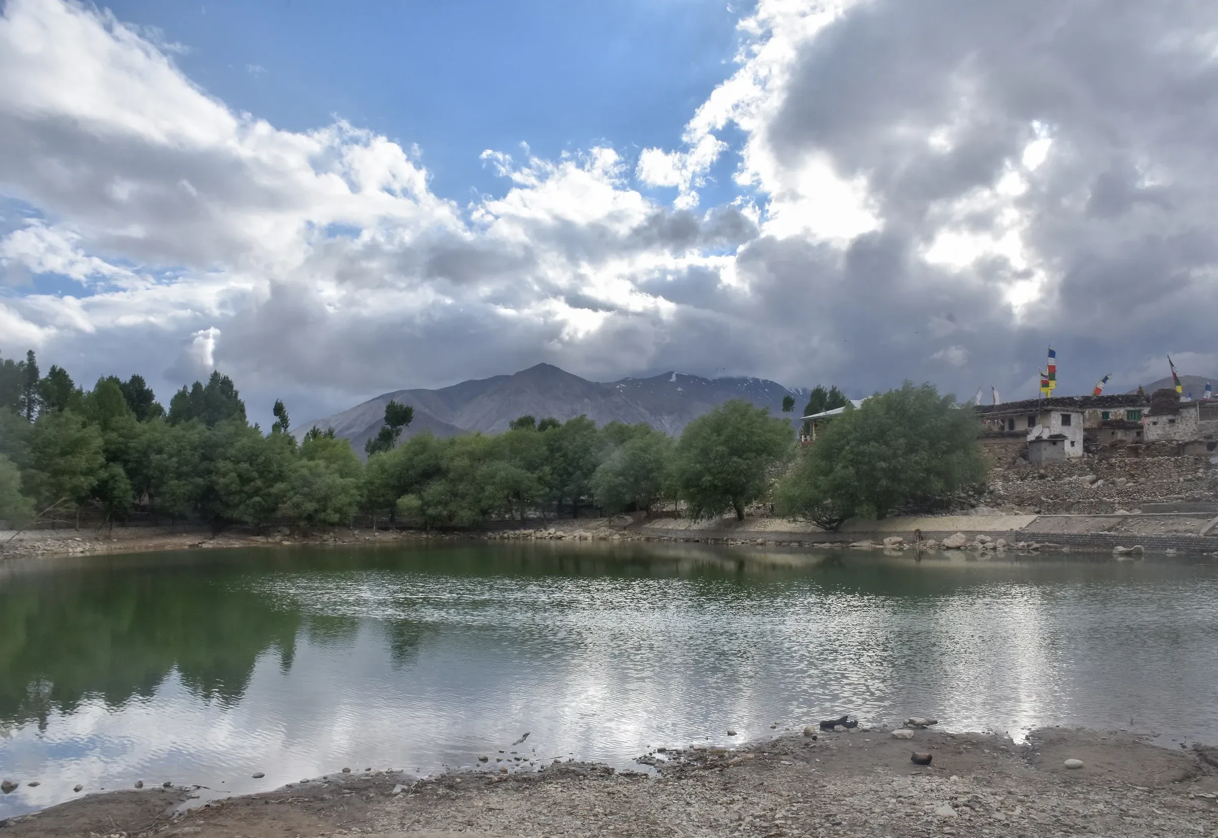 Nako Lake with village houses and prayer flags beneath dry mountains in Kinnaur