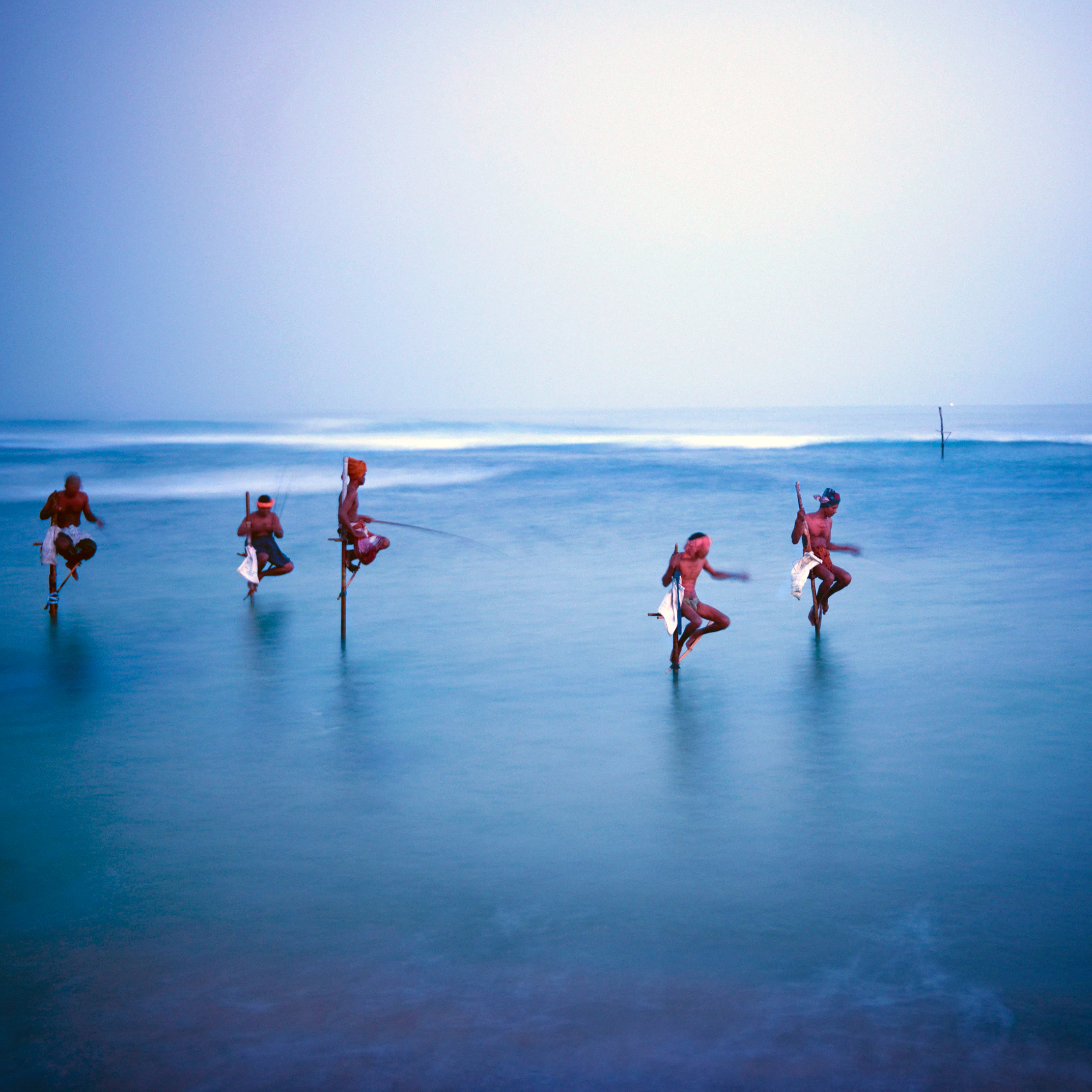 Stilt fishermen standing in shallow water on Sri Lanka's south coast