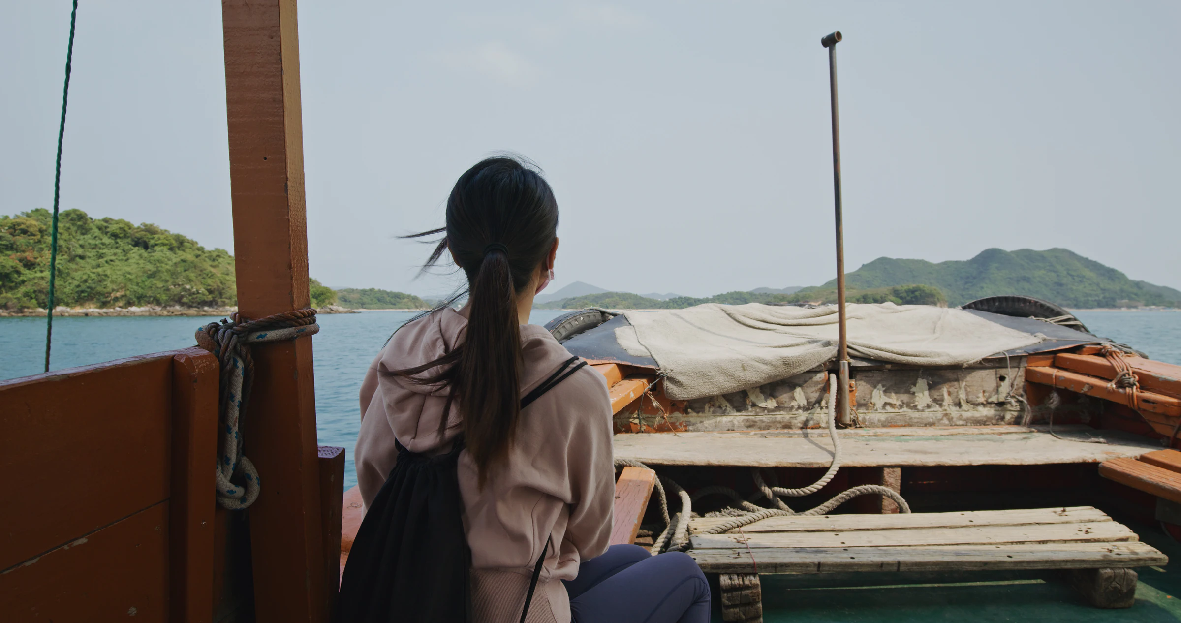 A traveller on a wooden boat looking back at the islands