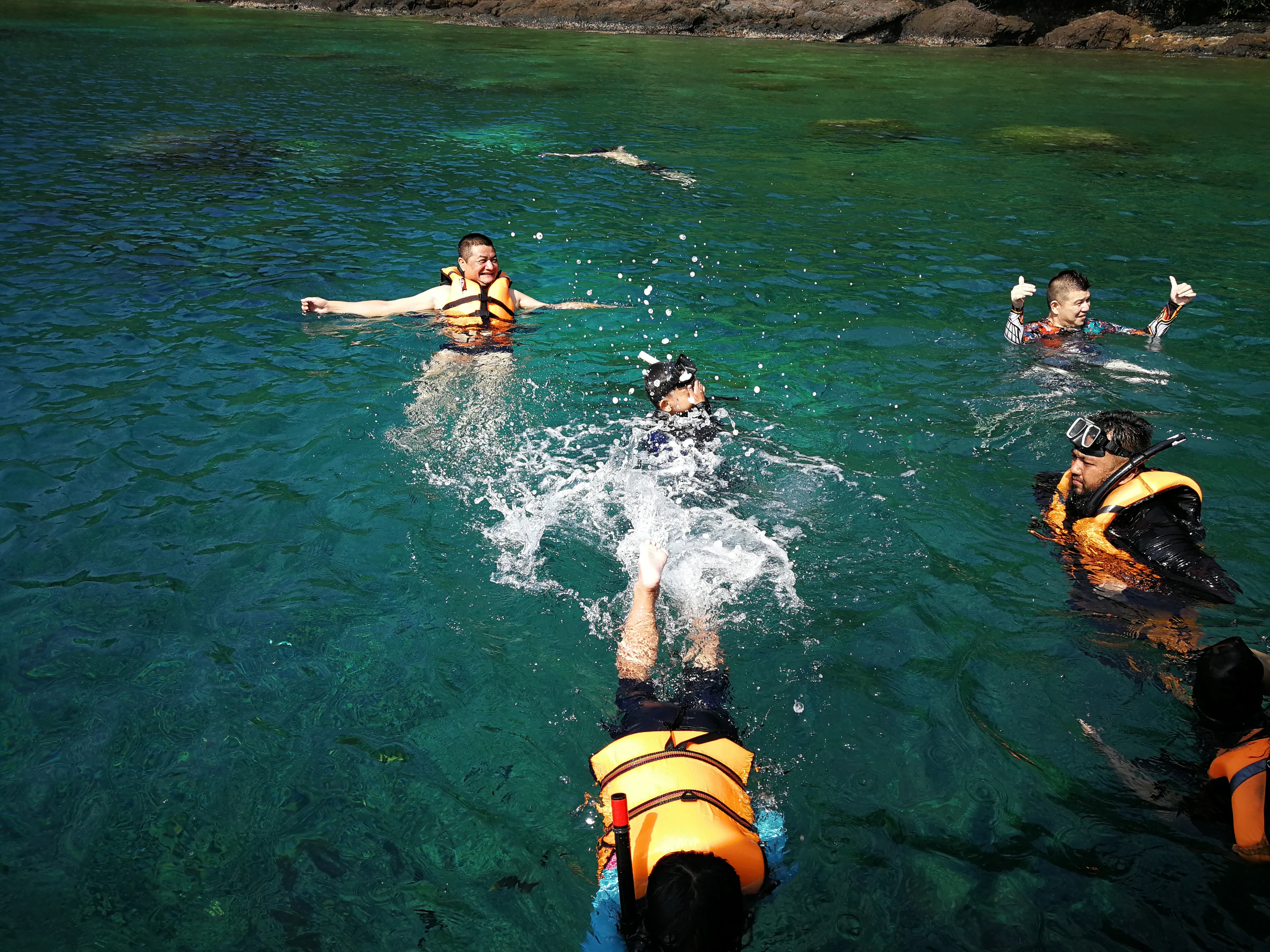 A group snorkelling off a boat in clear water