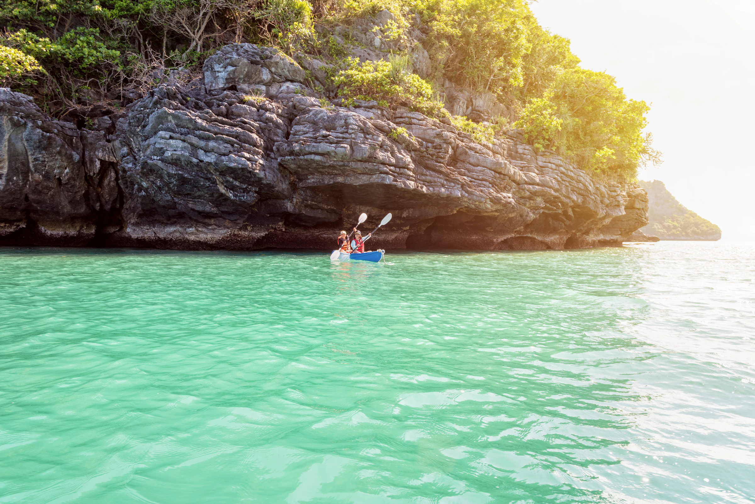 A kayaker paddling beneath a limestone island