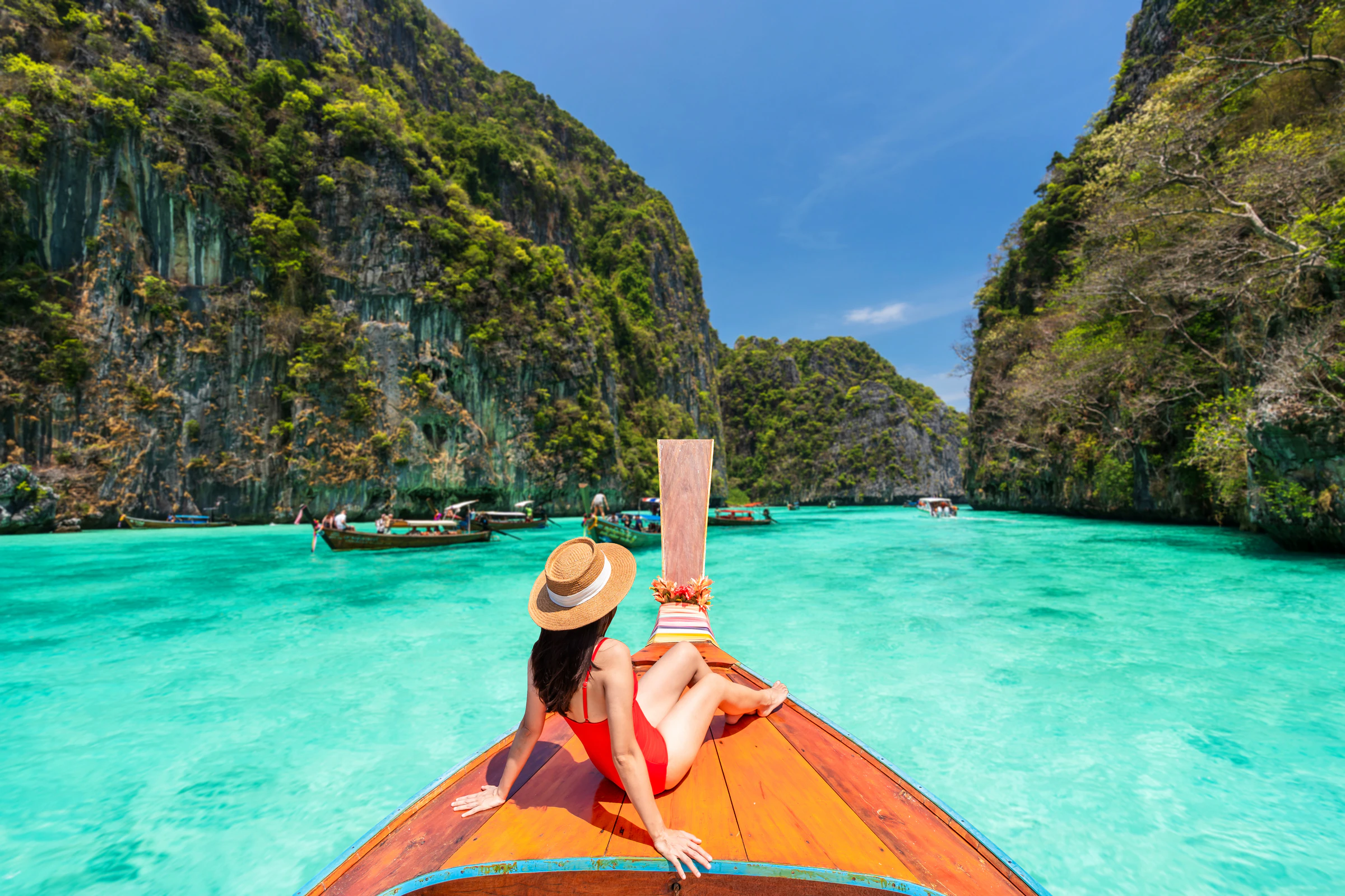 A traveller sitting on the bow of a longtail boat in Pileh Lagoon, Phi Phi