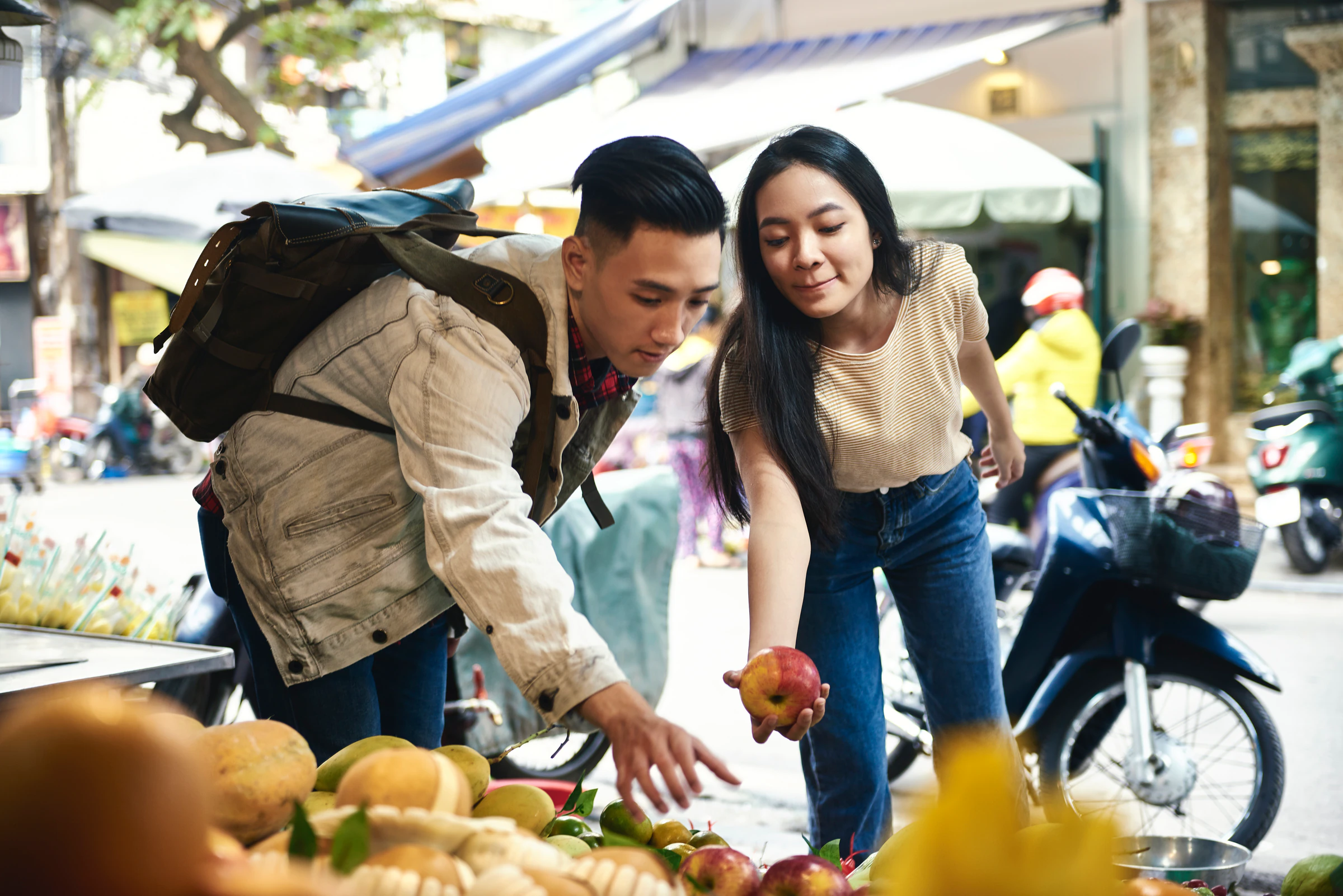 Two travellers choosing fruit at a street market stall
