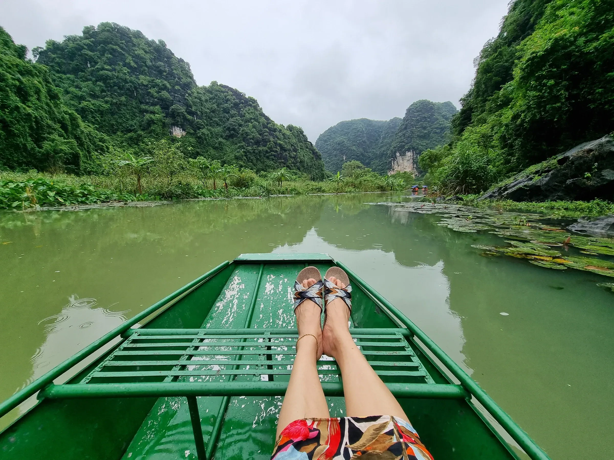 Sitting in the bow of a rowing boat between limestone cliffs in Ninh Binh