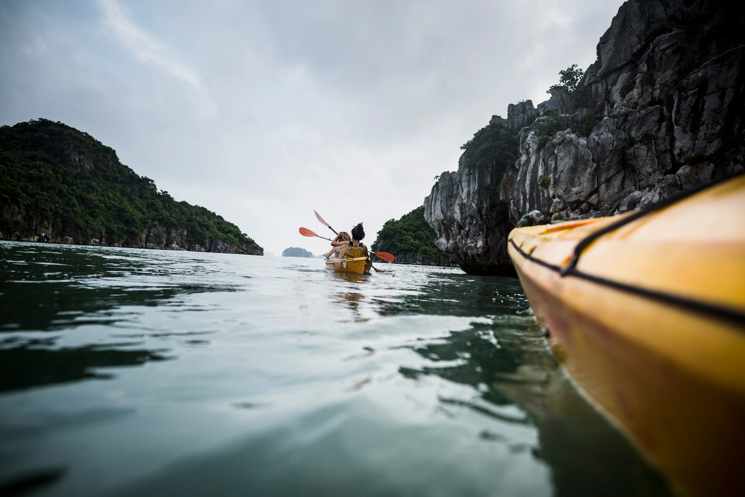A group of kayakers paddling between limestone islands in the bay