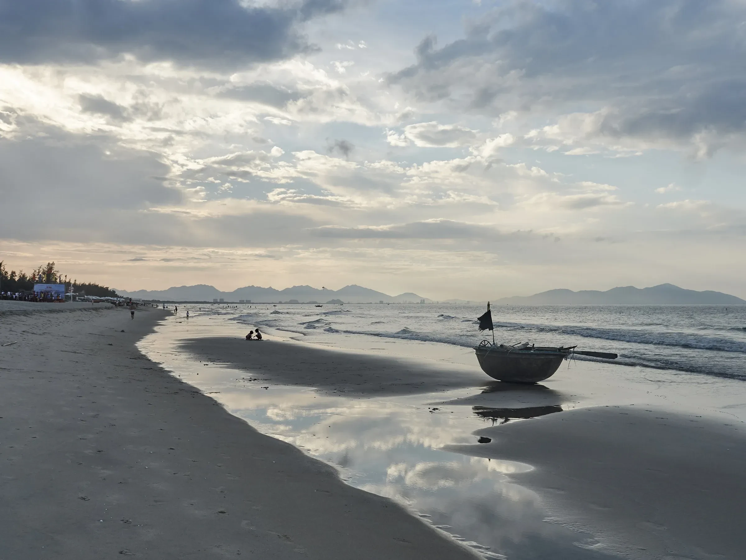 A round basket boat on the sand at An Bang beach near Hoi An, with the evening sky in the wet sand