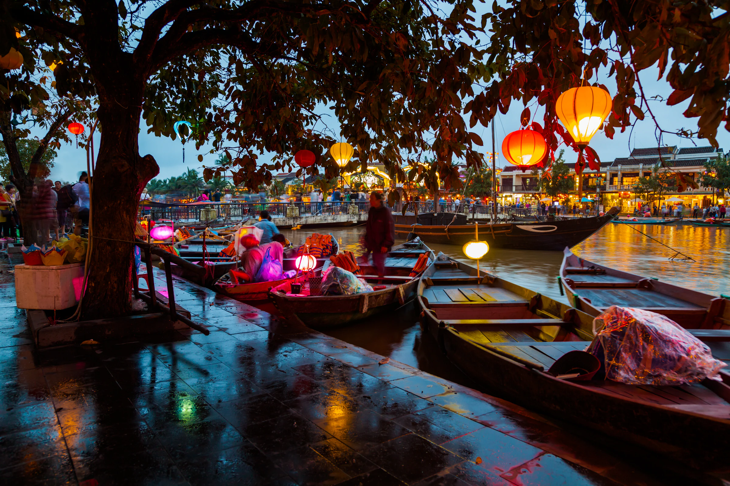 Wooden boats and lanterns on the riverbank in Hoi An at dusk
