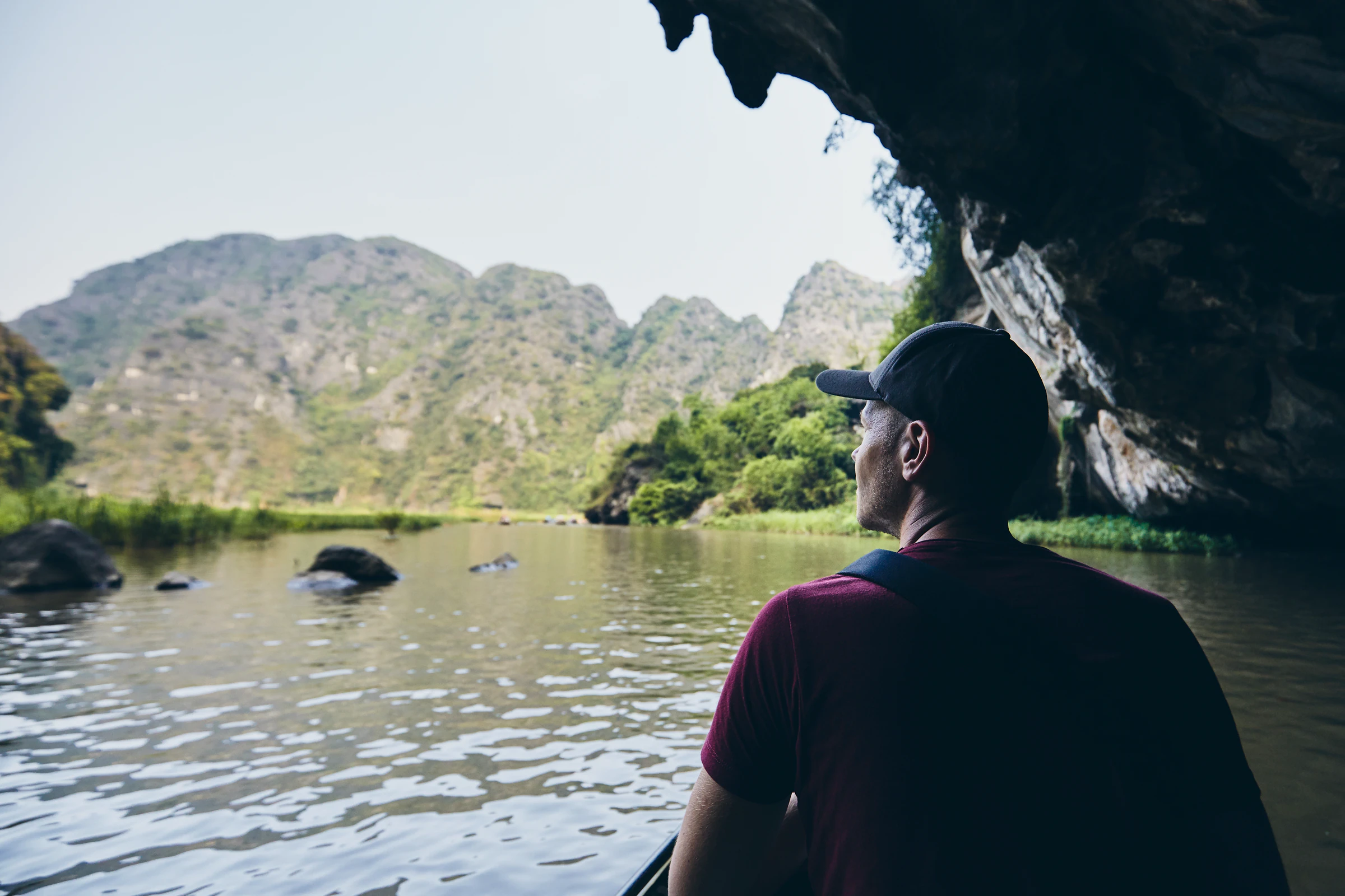 A traveller on a rowing boat at the mouth of a cave in Ninh Binh