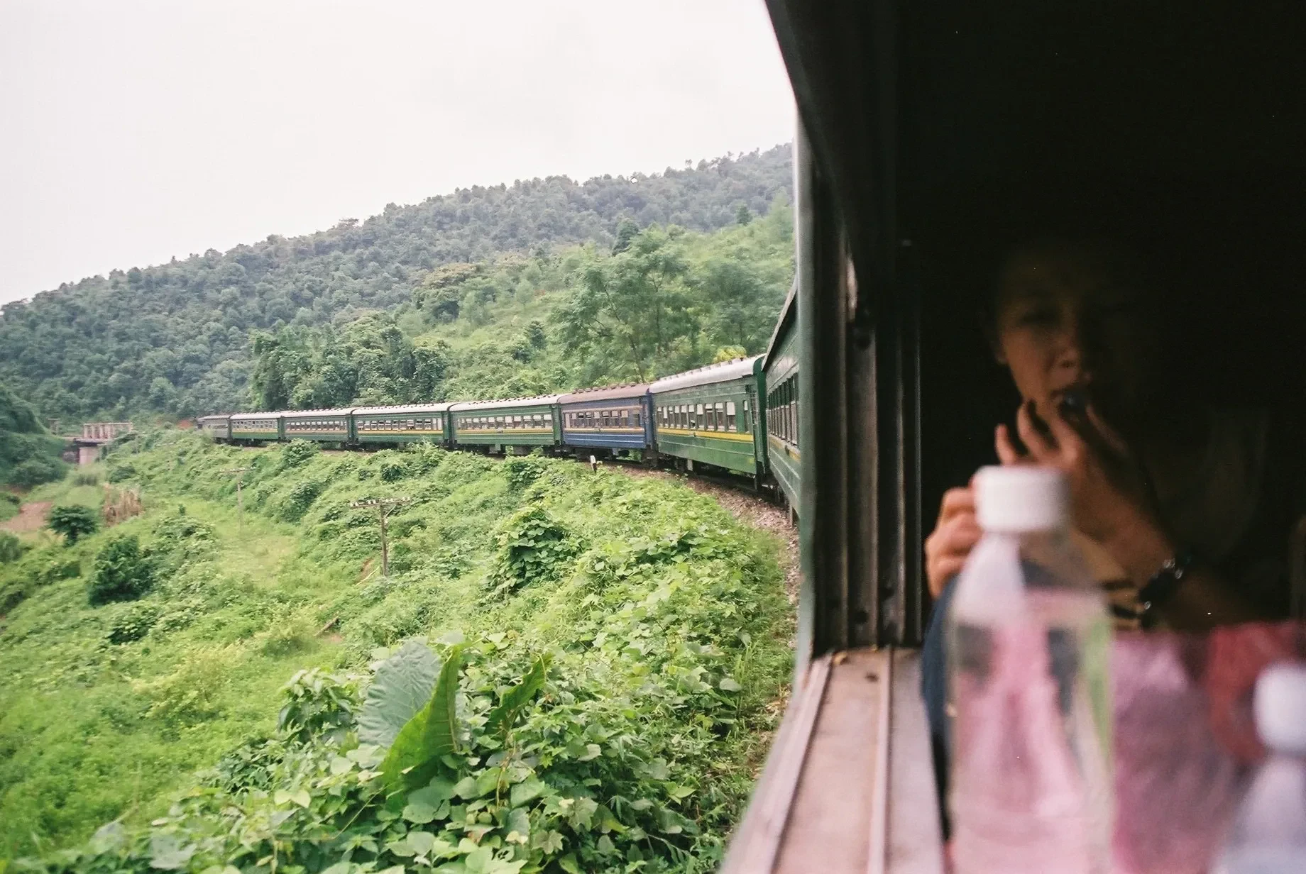 Looking out of a Reunification Express carriage window as the train curves through green hills